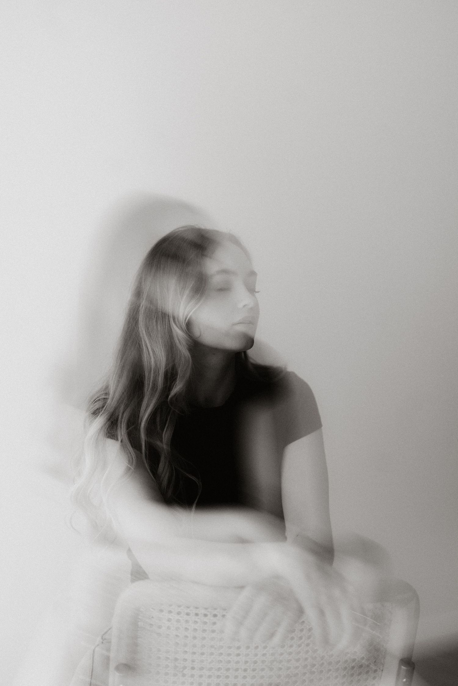Multiple exposure black and white portrait showing motion blur of person in white sweater turning their head.