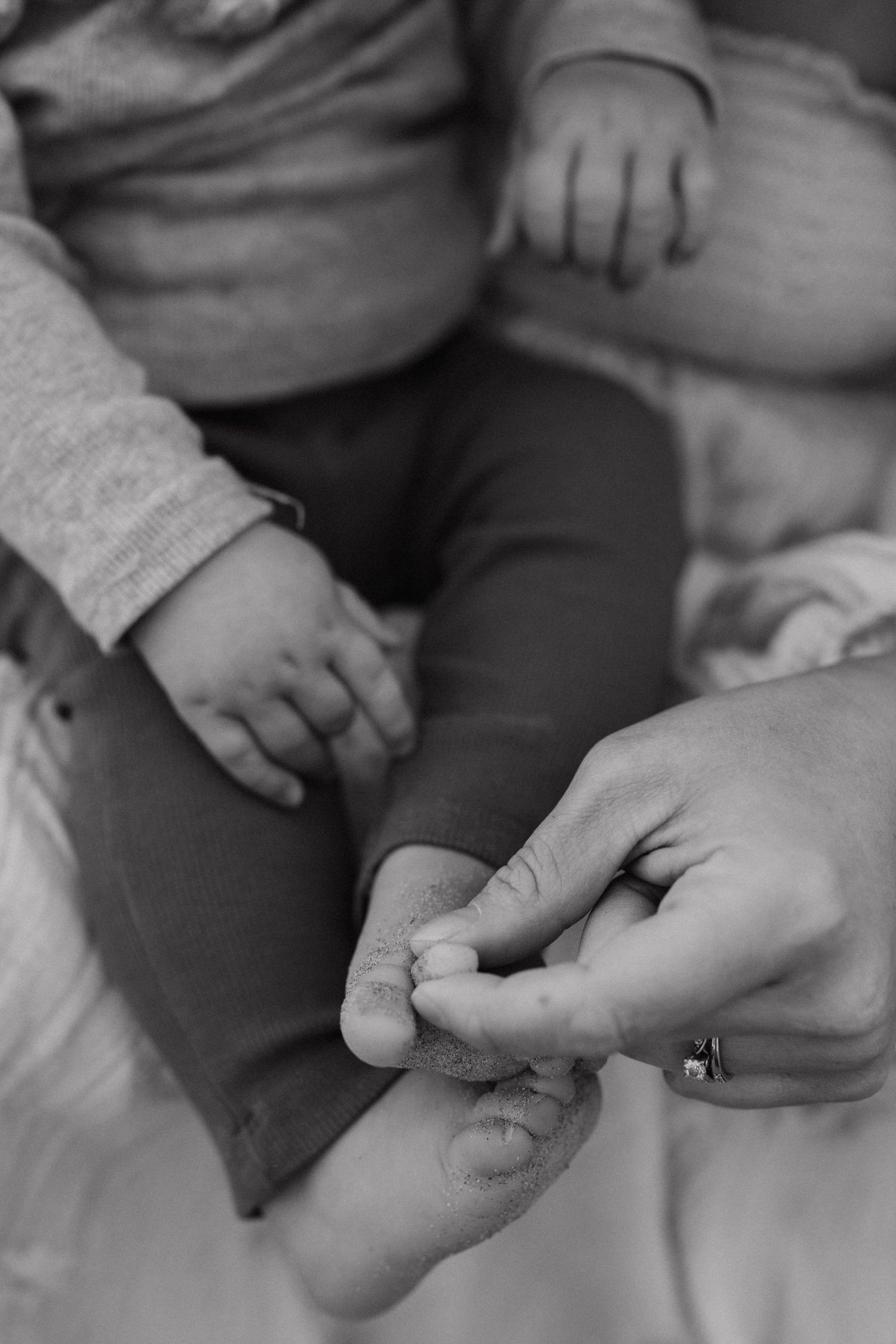 Close-up black and white image of gentle hand holding small feet.