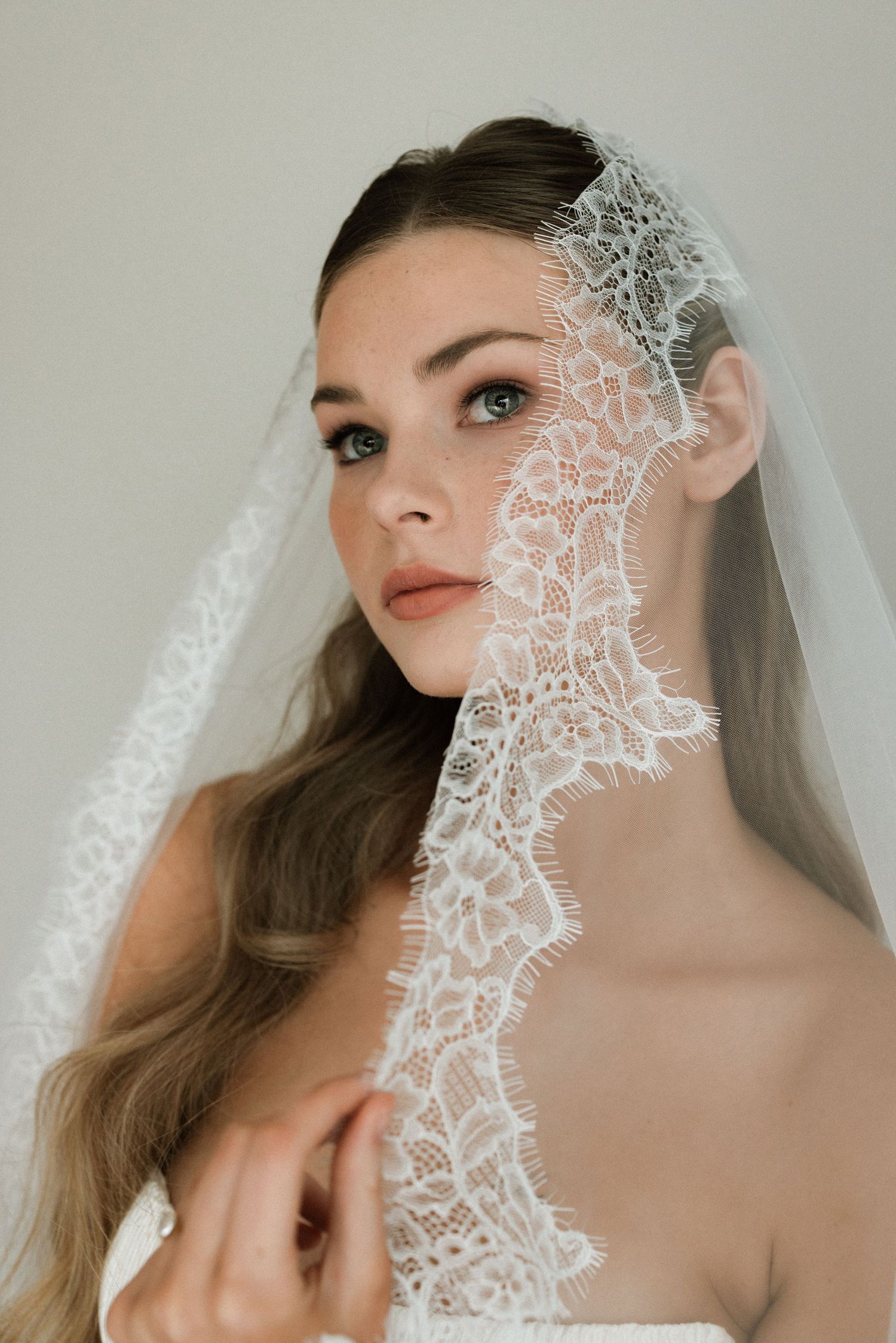 Delicate lace veil creates romantic framing in bridal portrait series.
