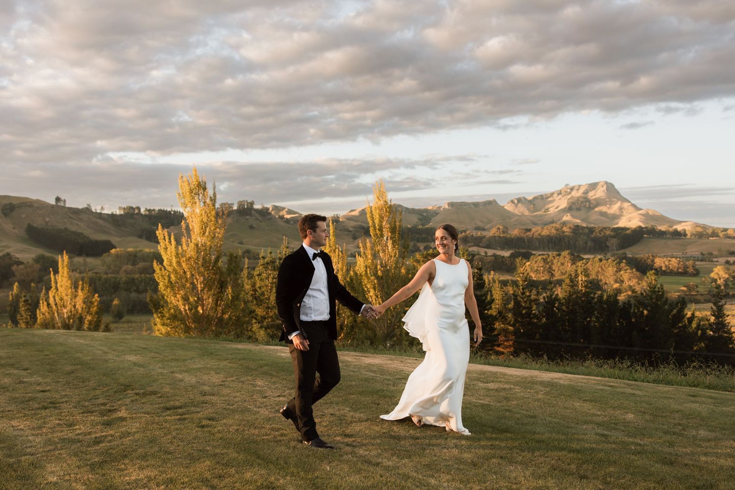 Wedding couple photographed against scenic mountain landscape at golden hour.