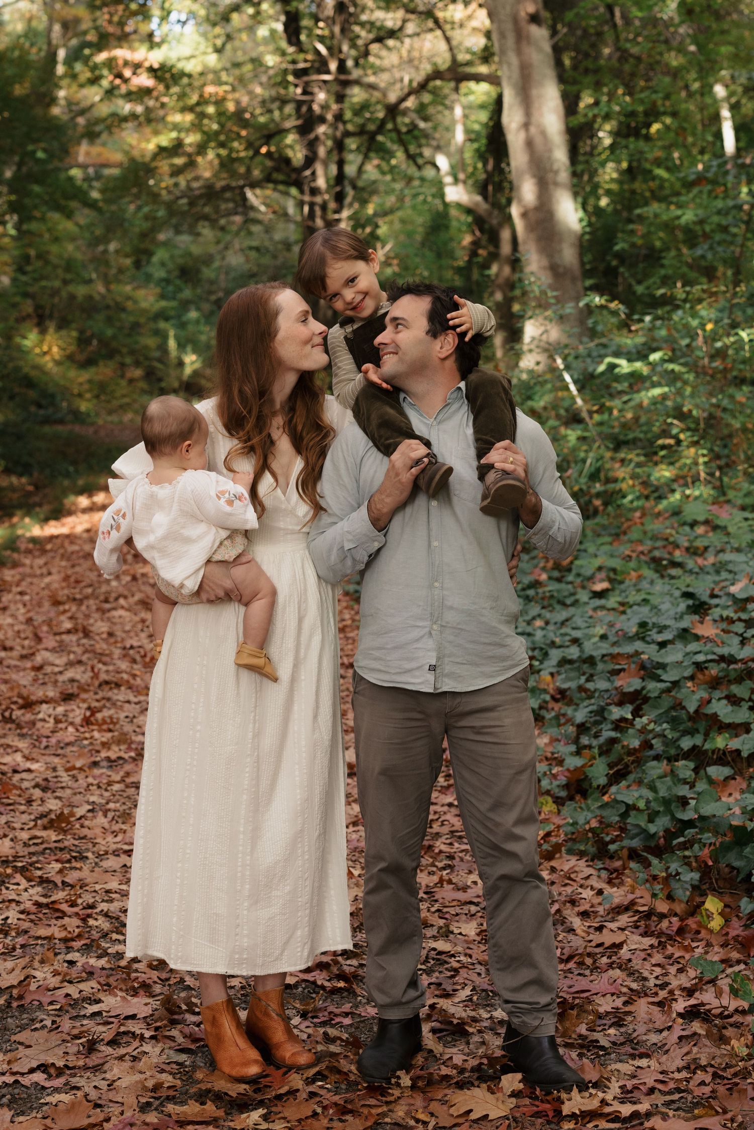 A joyful family moment captured on an autumn trail surrounded by fallen leaves.