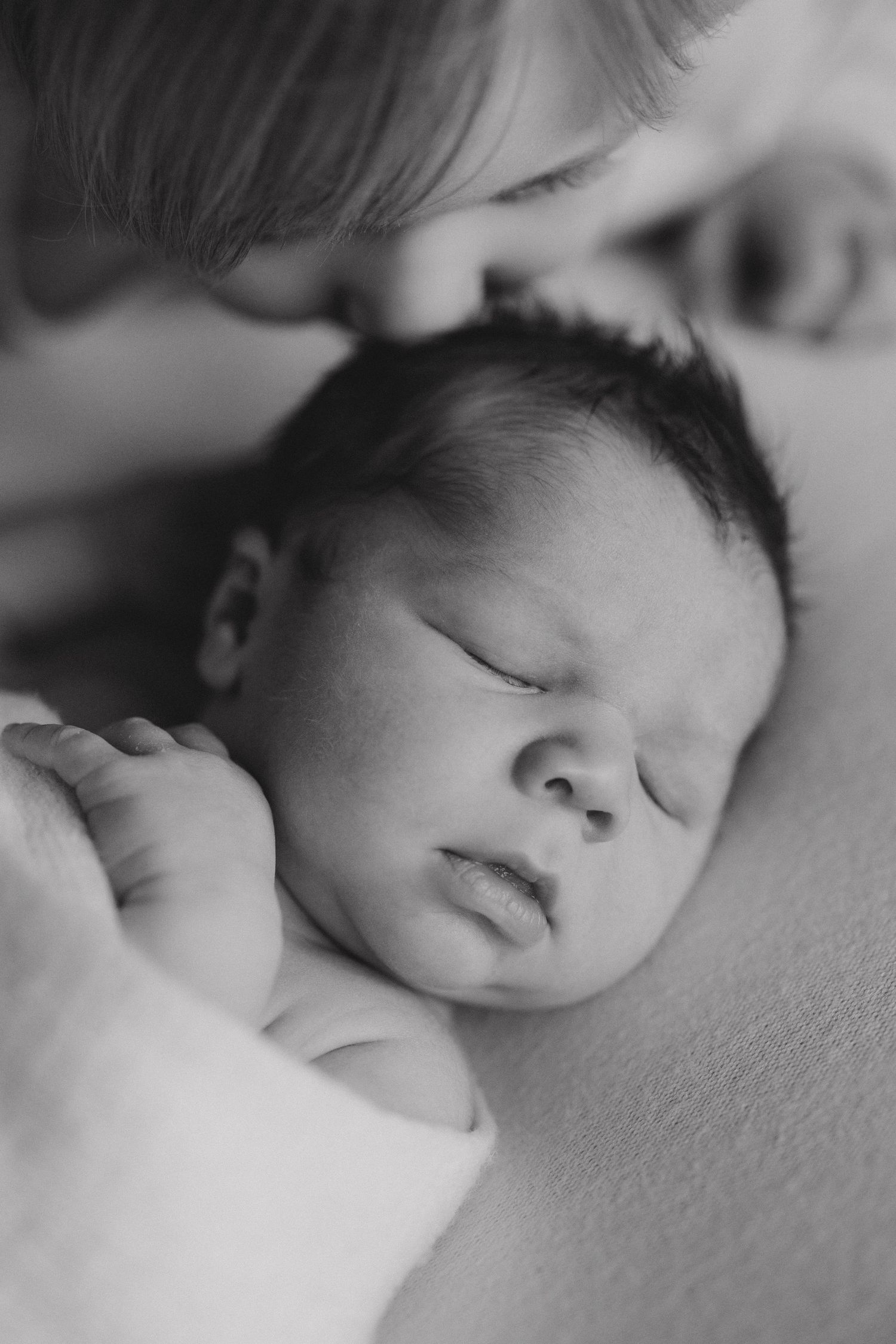 Artistic black and white close-up of sleeping baby on soft surface.