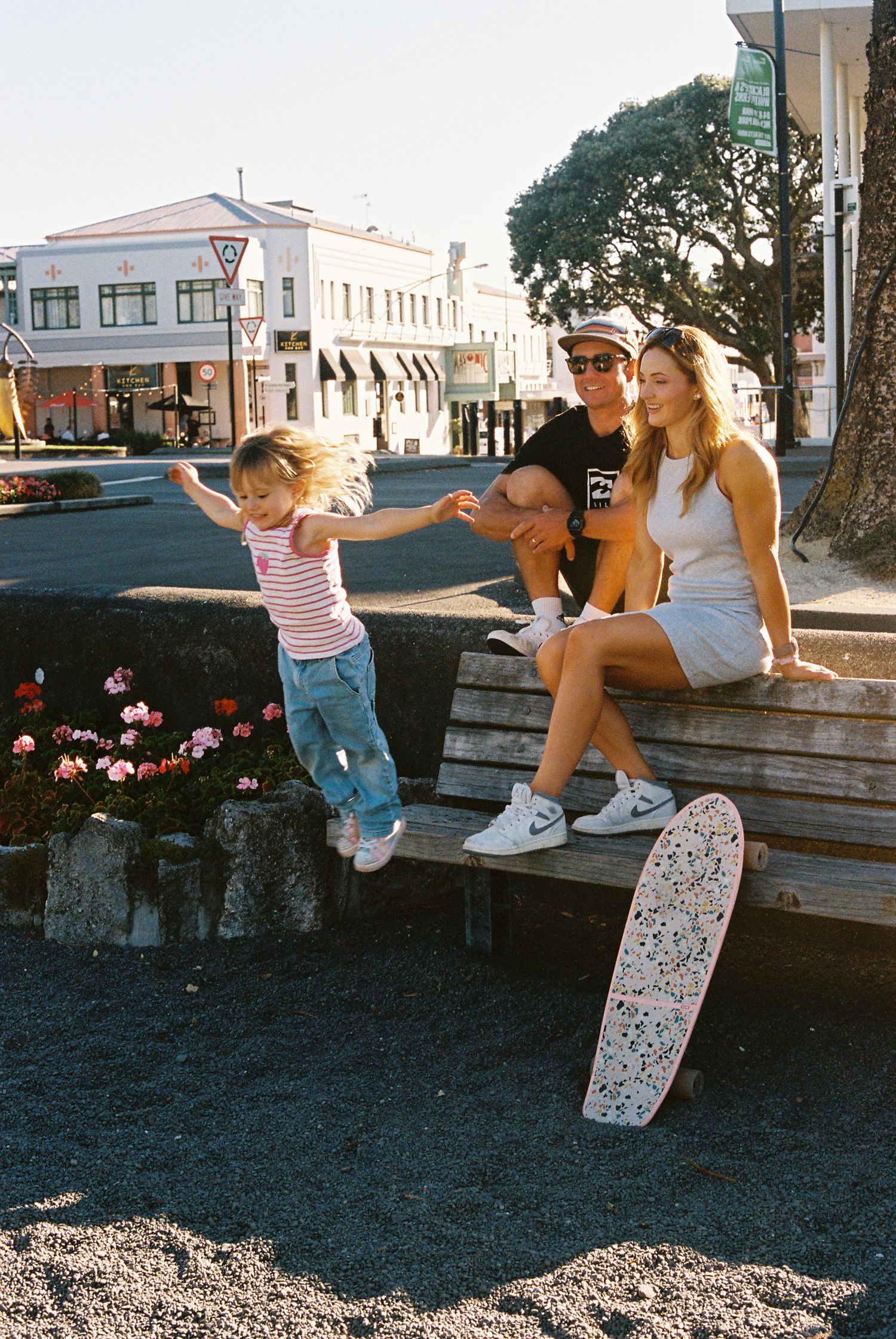 People enjoying skateboarding tricks on a low wall during sunset.