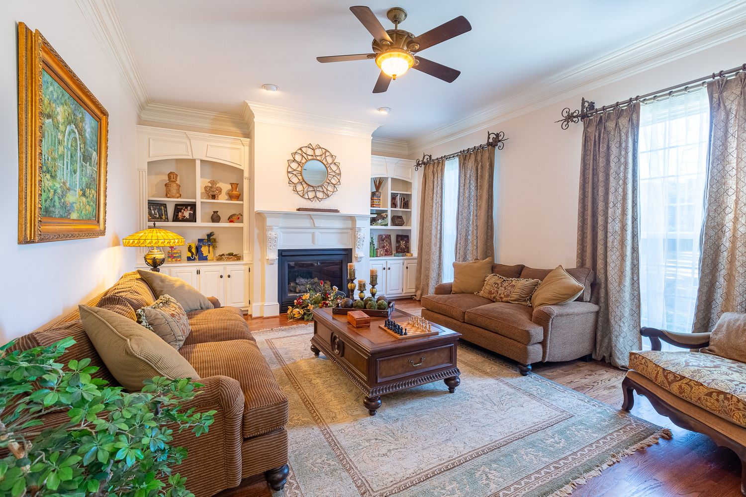 Cozy living room with brown leather sofas, built-in shelving, and a central fireplace.