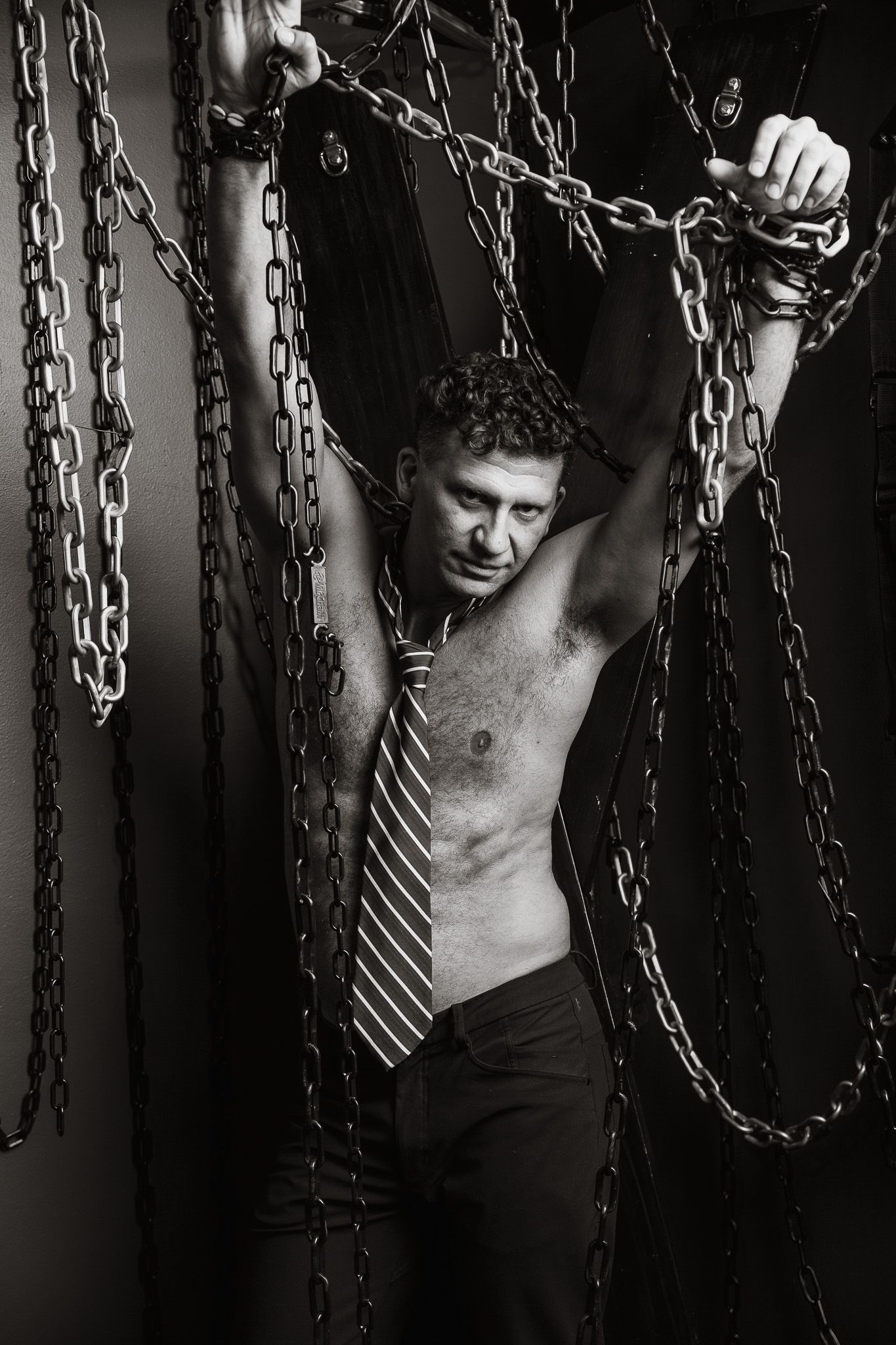 Artistic black and white photo featuring chains and business tie creating contrast.