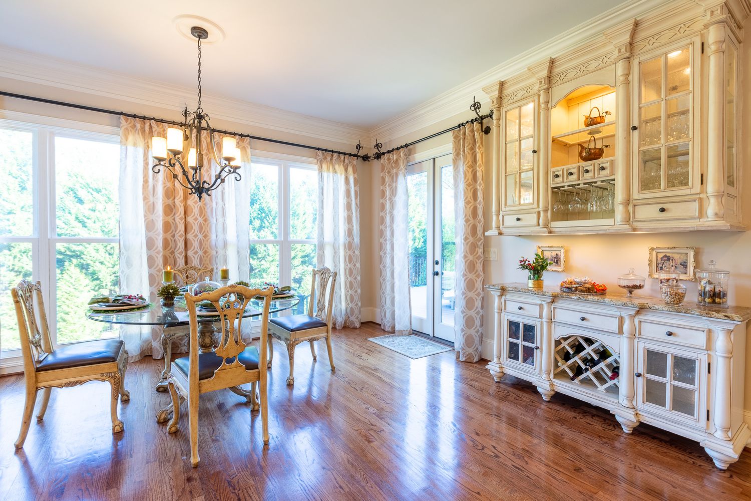 Elegant white kitchen with glass cabinets, chandelier lighting and wine storage.
