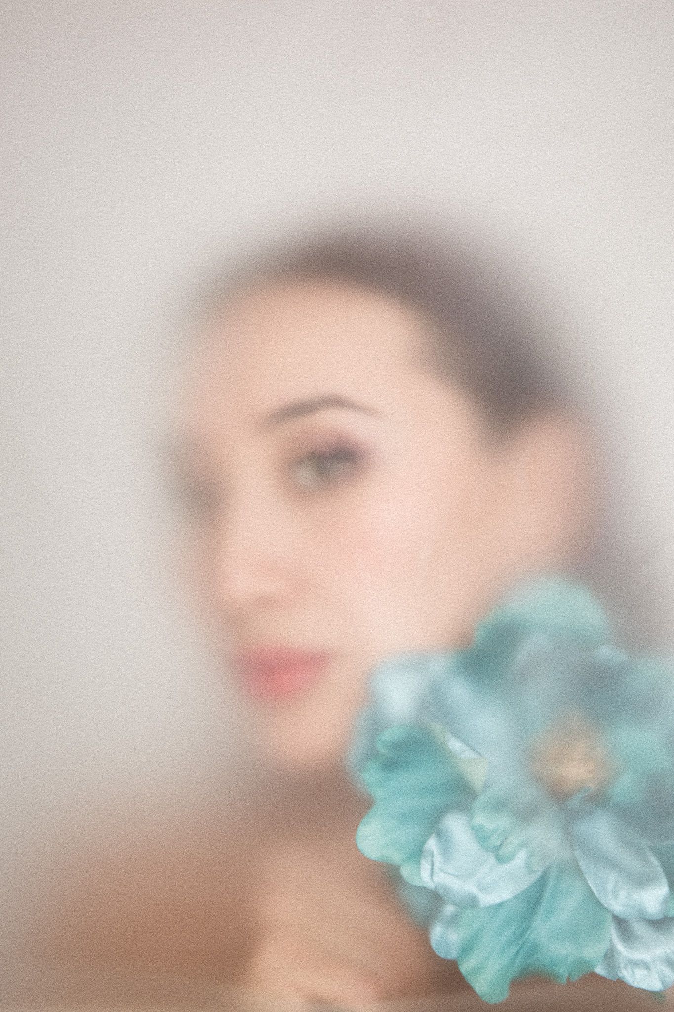 Artistic portrait with soft focus and turquoise floral accents creating an ethereal effect.