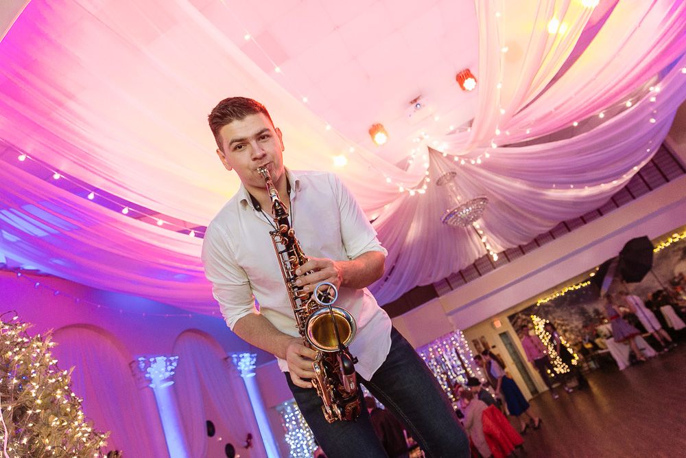 Musicians performing with saxophones at an event with pink and purple lighting effects.