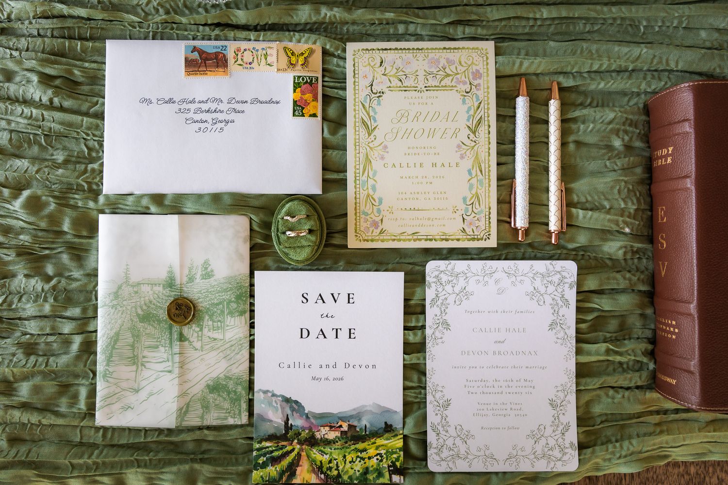 Elegant wedding stationery suite with save the date, invitations, envelope, and gold wax seal on green silk fabric.