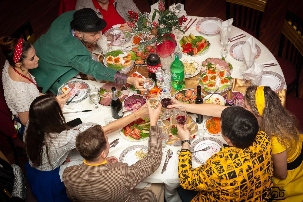 Large group enjoying a festive dinner party with colorful food spread on table.
