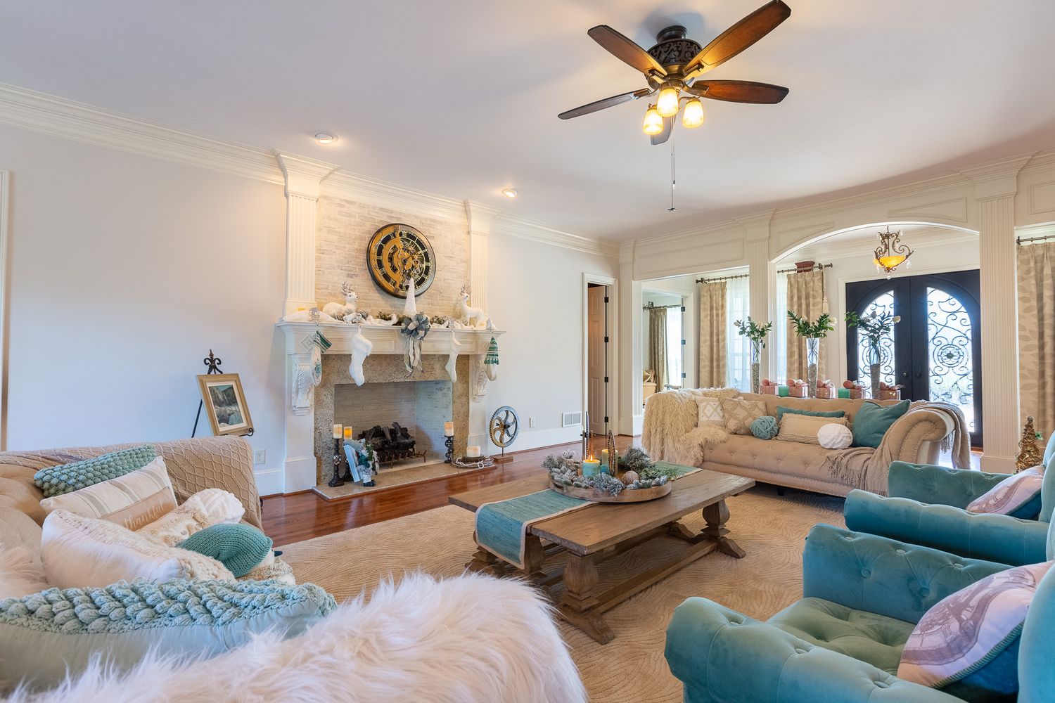 Living room with coastal-inspired decor featuring turquoise seating and white accents around a stone fireplace.