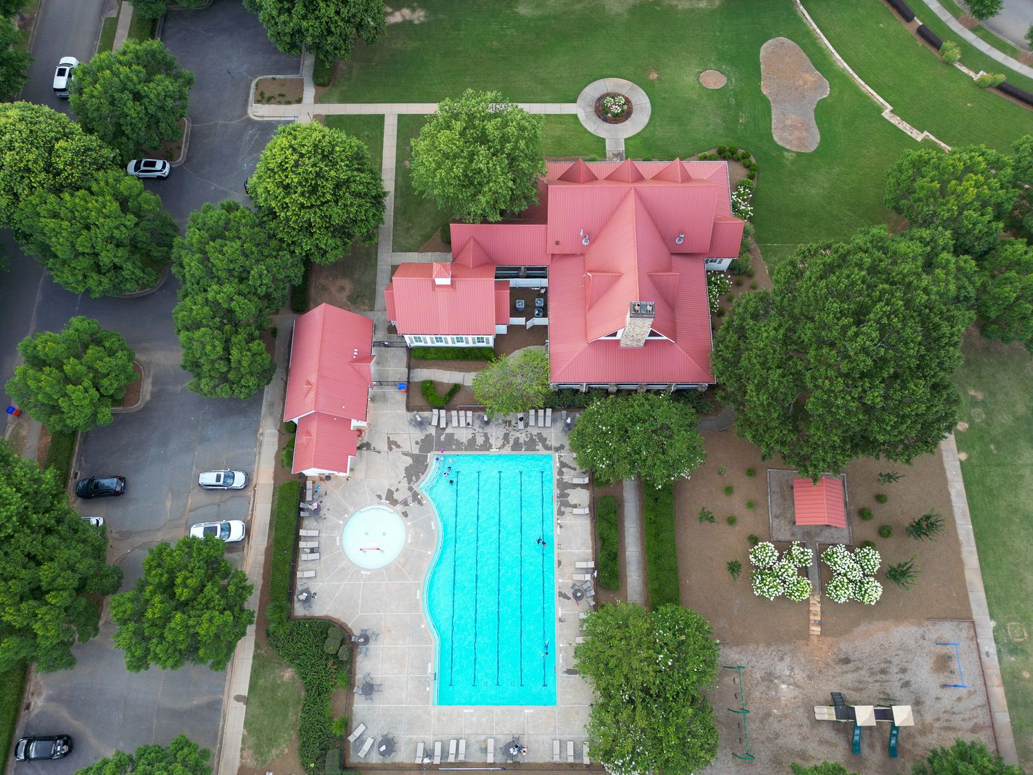 Aerial view of a community pool and recreational area with red-roofed buildings.