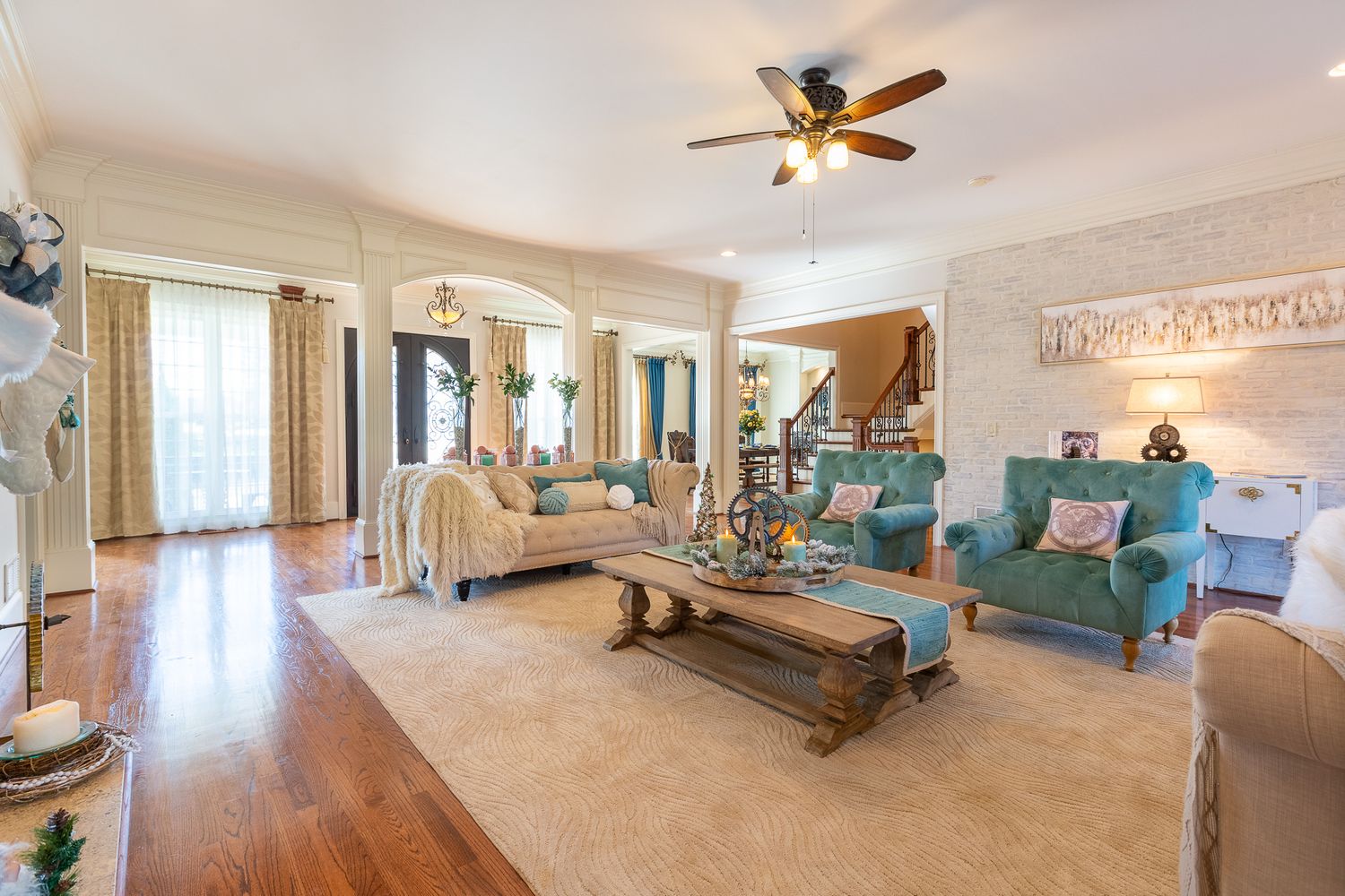 Large master bedroom with coffered ceiling, ceiling fan, and coastal-inspired furnishings in white and turquoise.