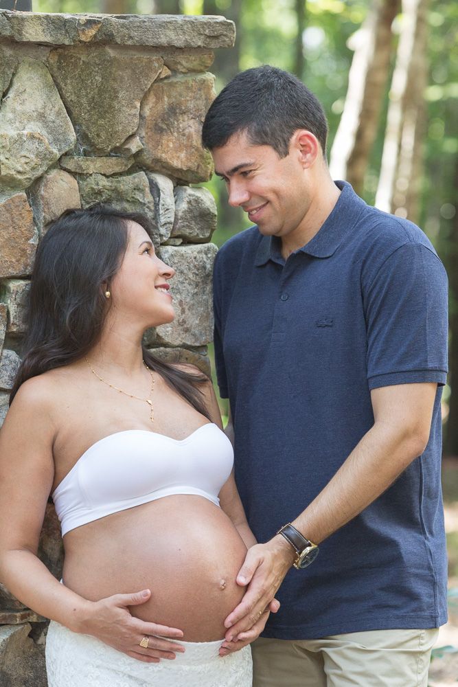 Maternity photo series showing a couple embracing outdoors against a stone wall in natural lighting.