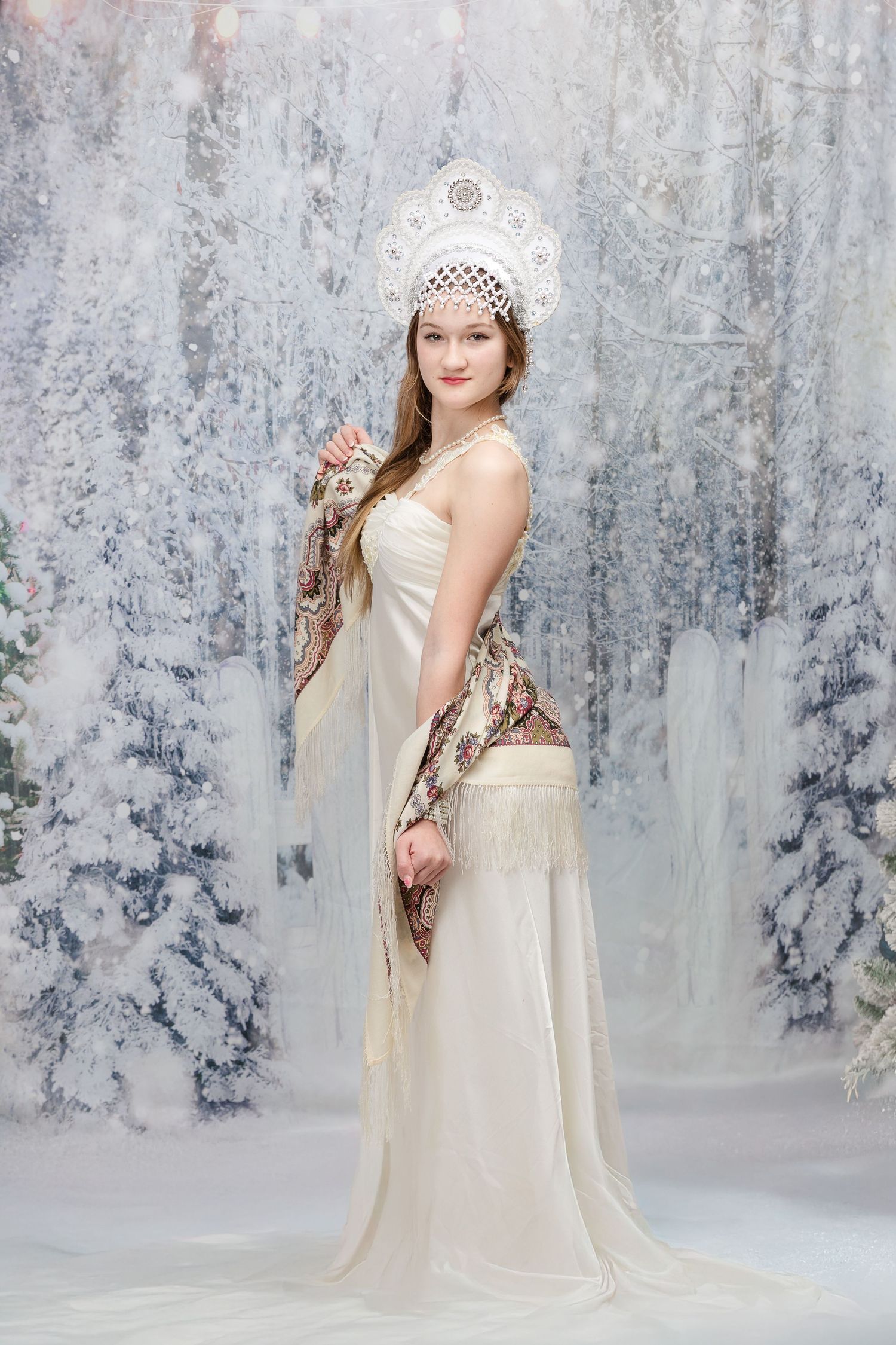 Ethereal maternity portraits in cream dress with lace crown in winter setting.
