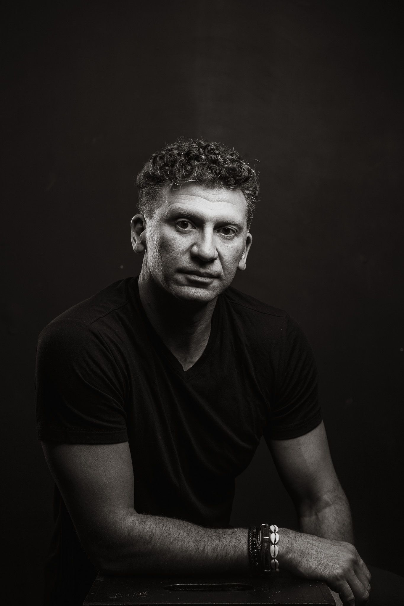 Moody black and white portrait with dramatic lighting against dark background.