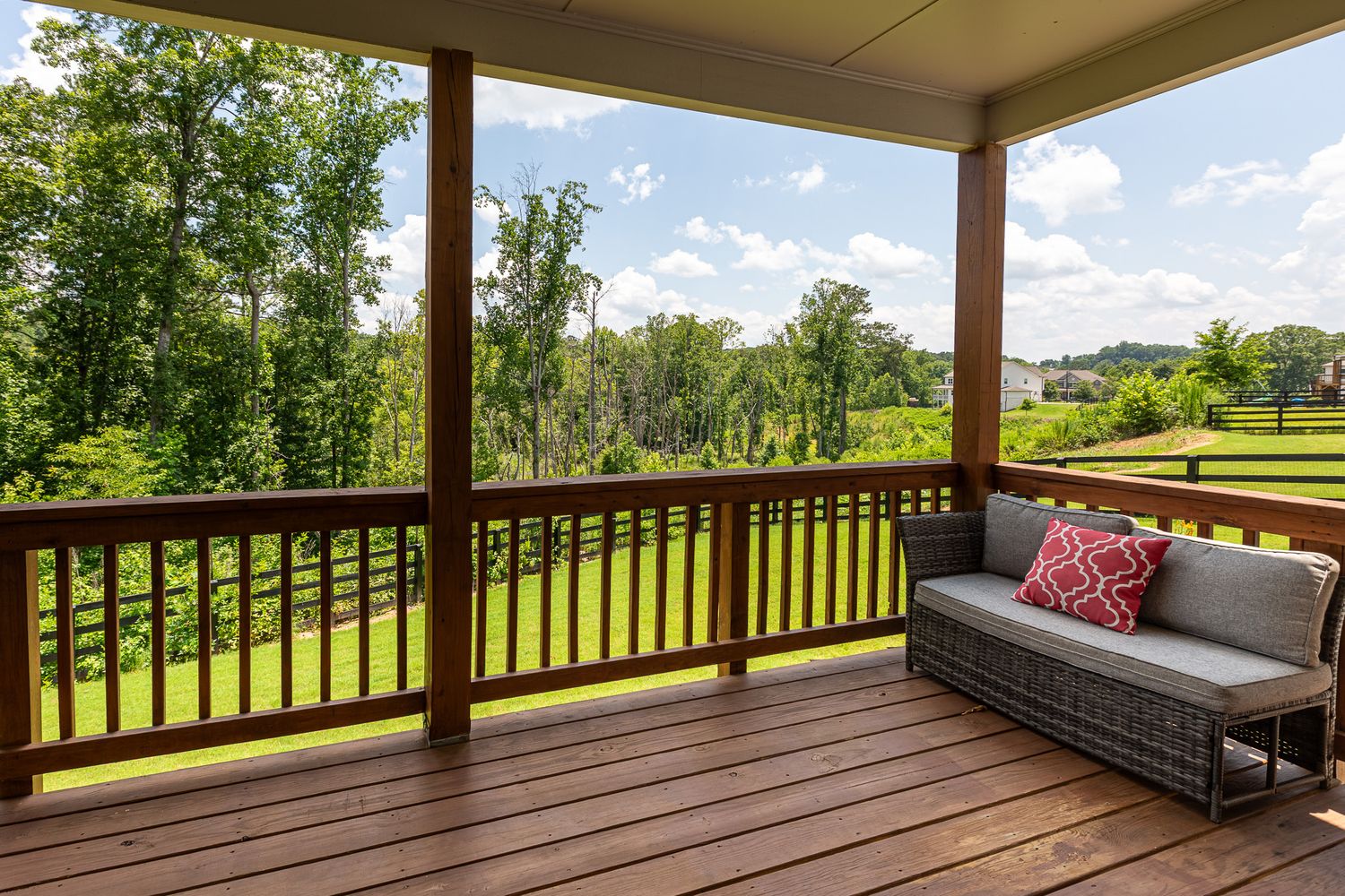 Expansive covered porch with wooden deck offering scenic views of surrounding landscape.
