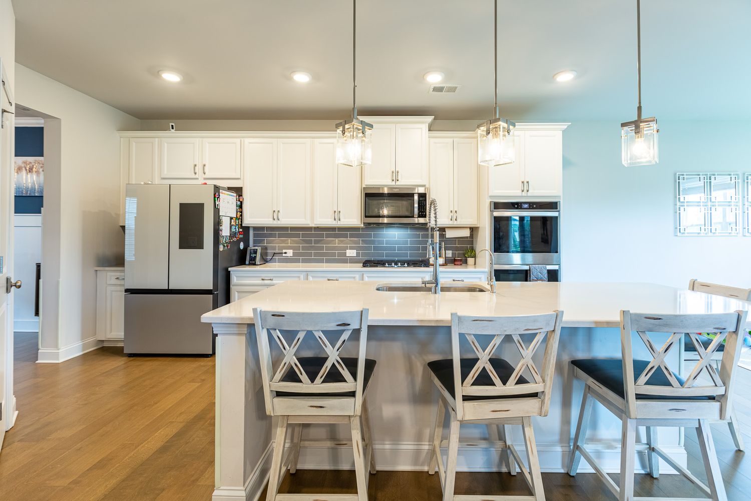 Modern open concept kitchen and dining area with white cabinets, pendant lights, and bar seating.