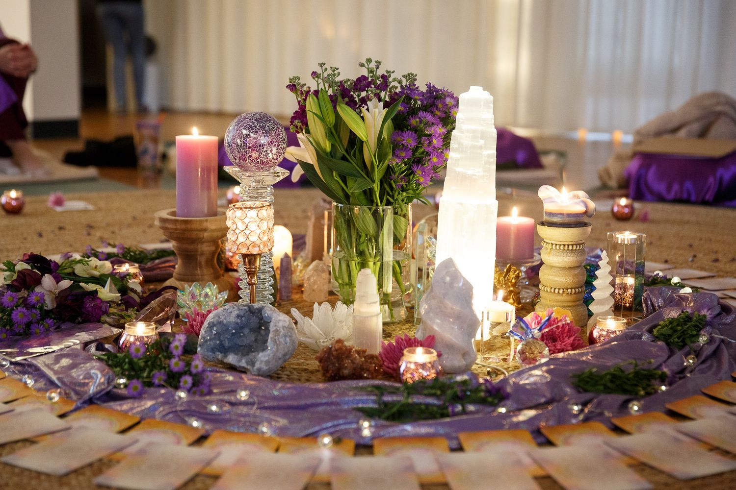 Crystal and floral centerpiece with candles and purple flowers on an elegant table setting.
