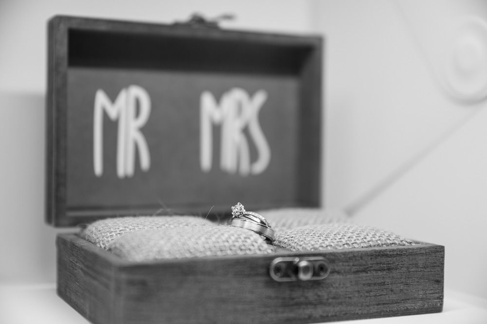 Black and white photo of wedding rings in a rustic wooden box labeled Mr and Mrs.