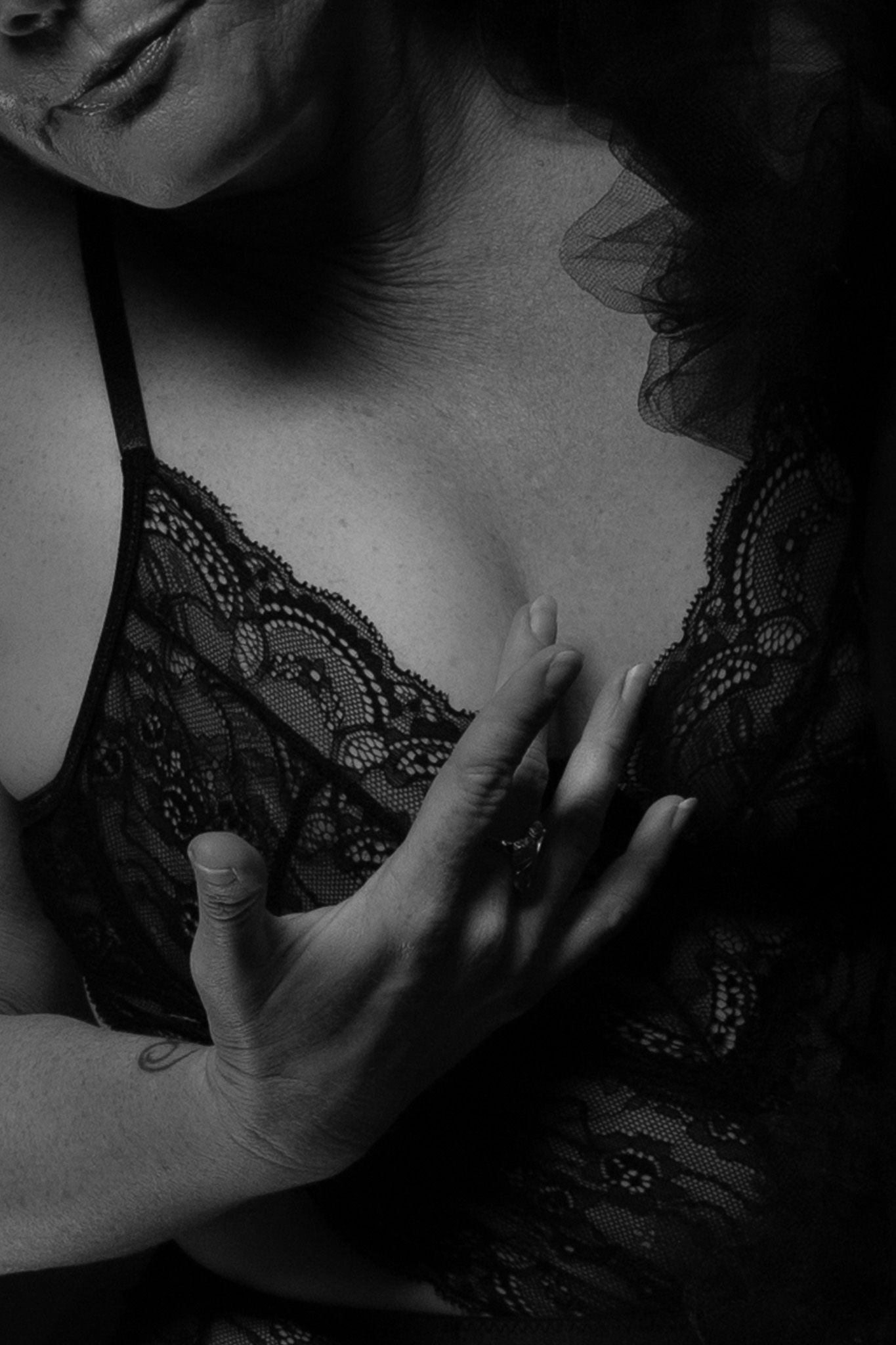 Artistic black and white photo showing hands in delicate lace lingerie creating sensual shadows and textures.