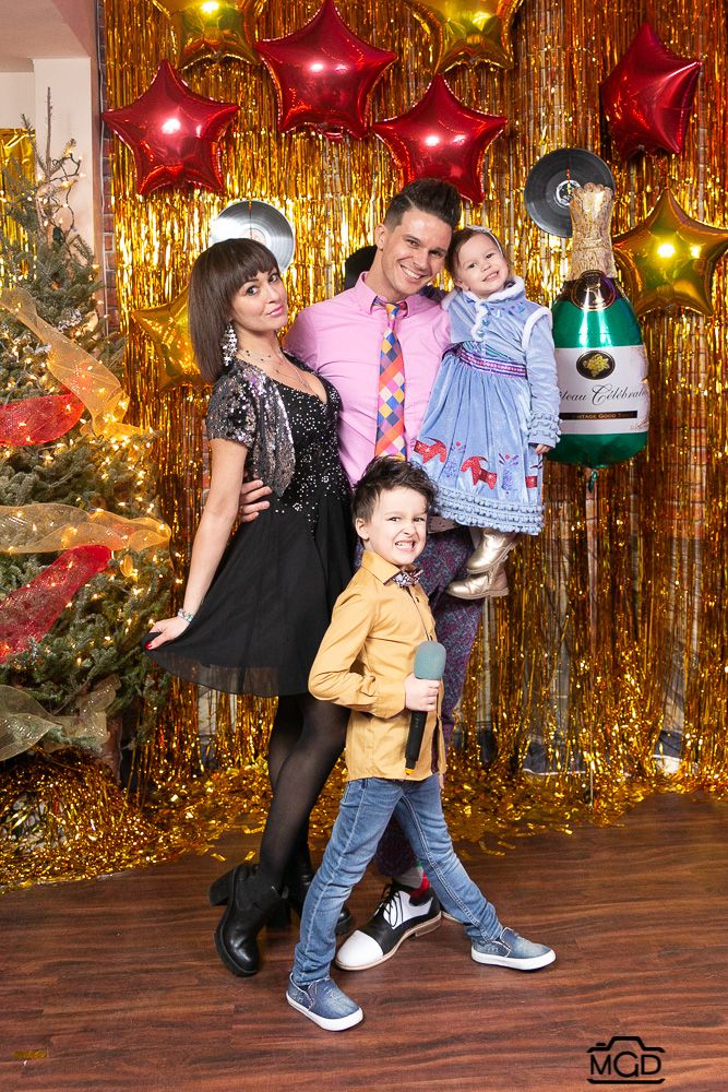 Family holiday photo session with gold tinsel backdrop and Christmas decorations.