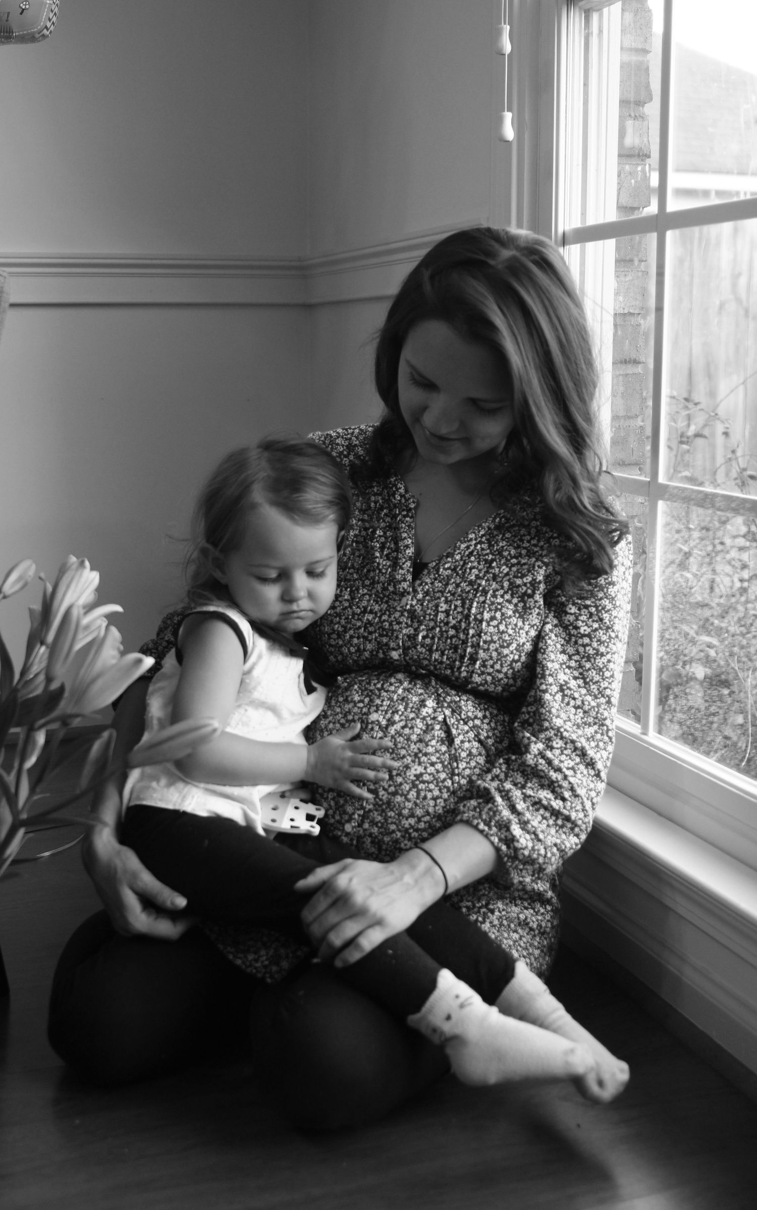 Black and white lifestyle photos of family bonding by window.