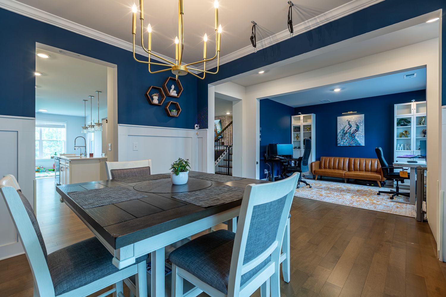 Modern dining area featuring a dark wood table, chandelier, and navy blue accent walls.