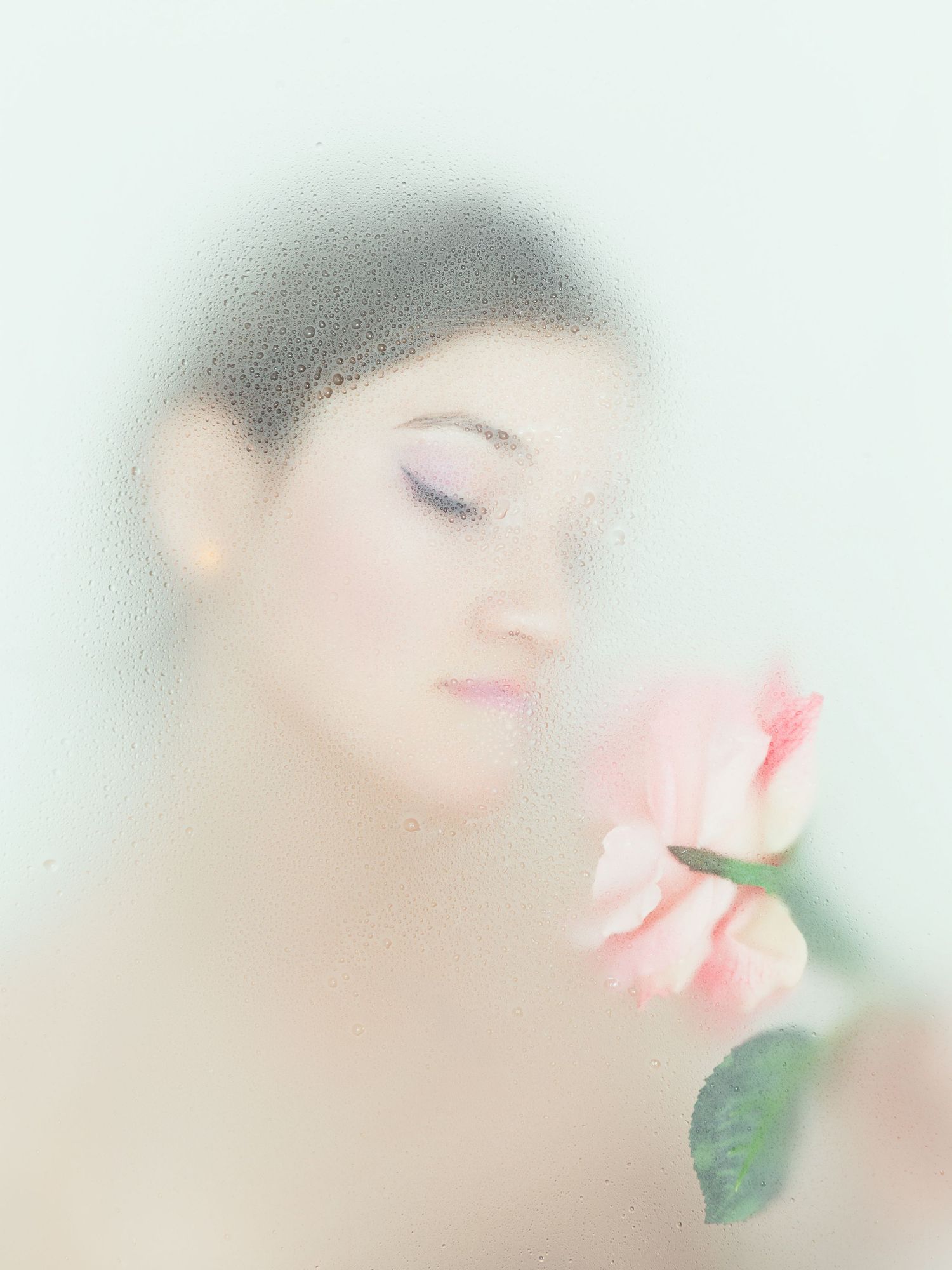 Dreamy portrait with soft focus effect and pink rose creating romantic ethereal mood.