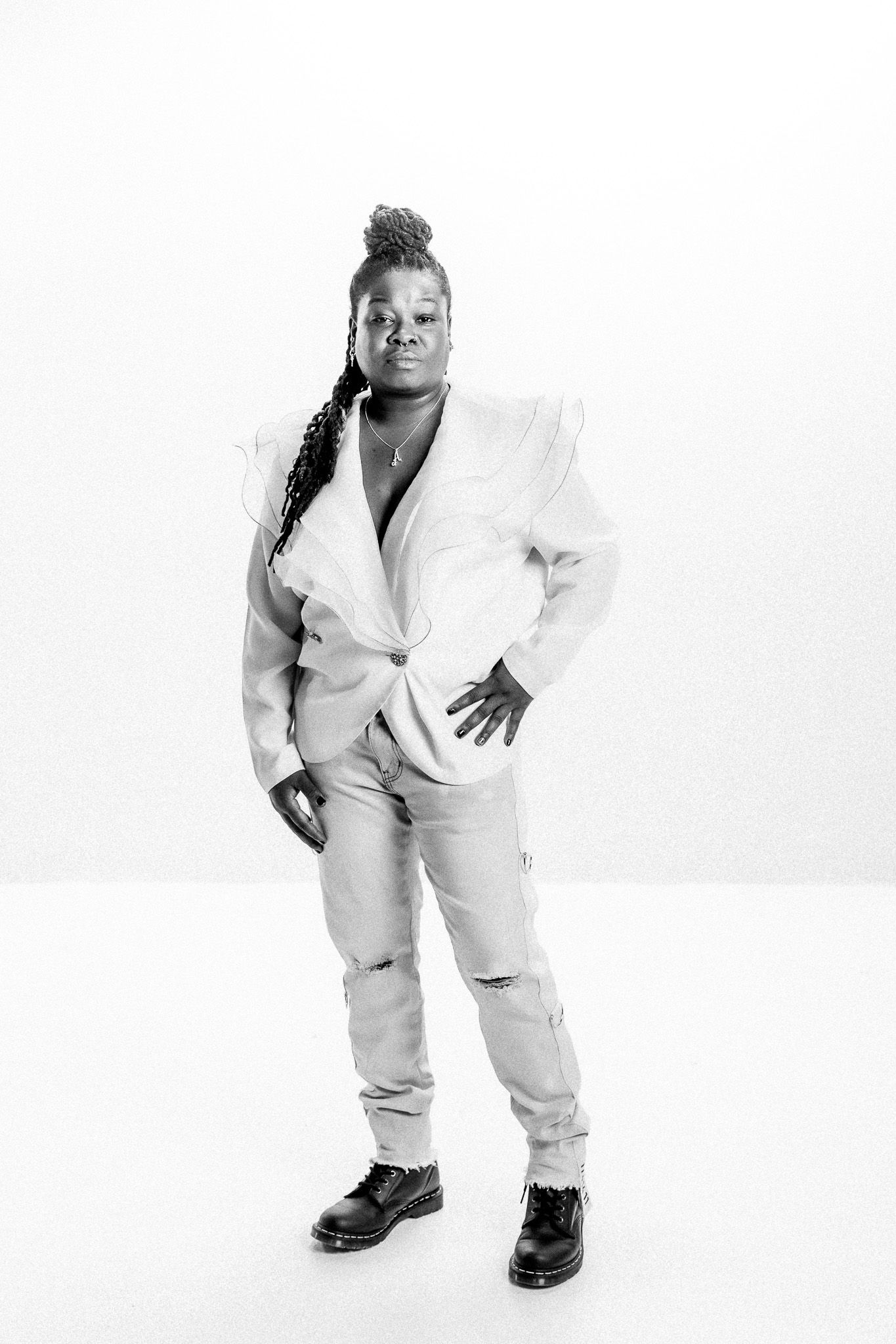 Monochrome fashion portrait showcasing white blazer and confident pose.