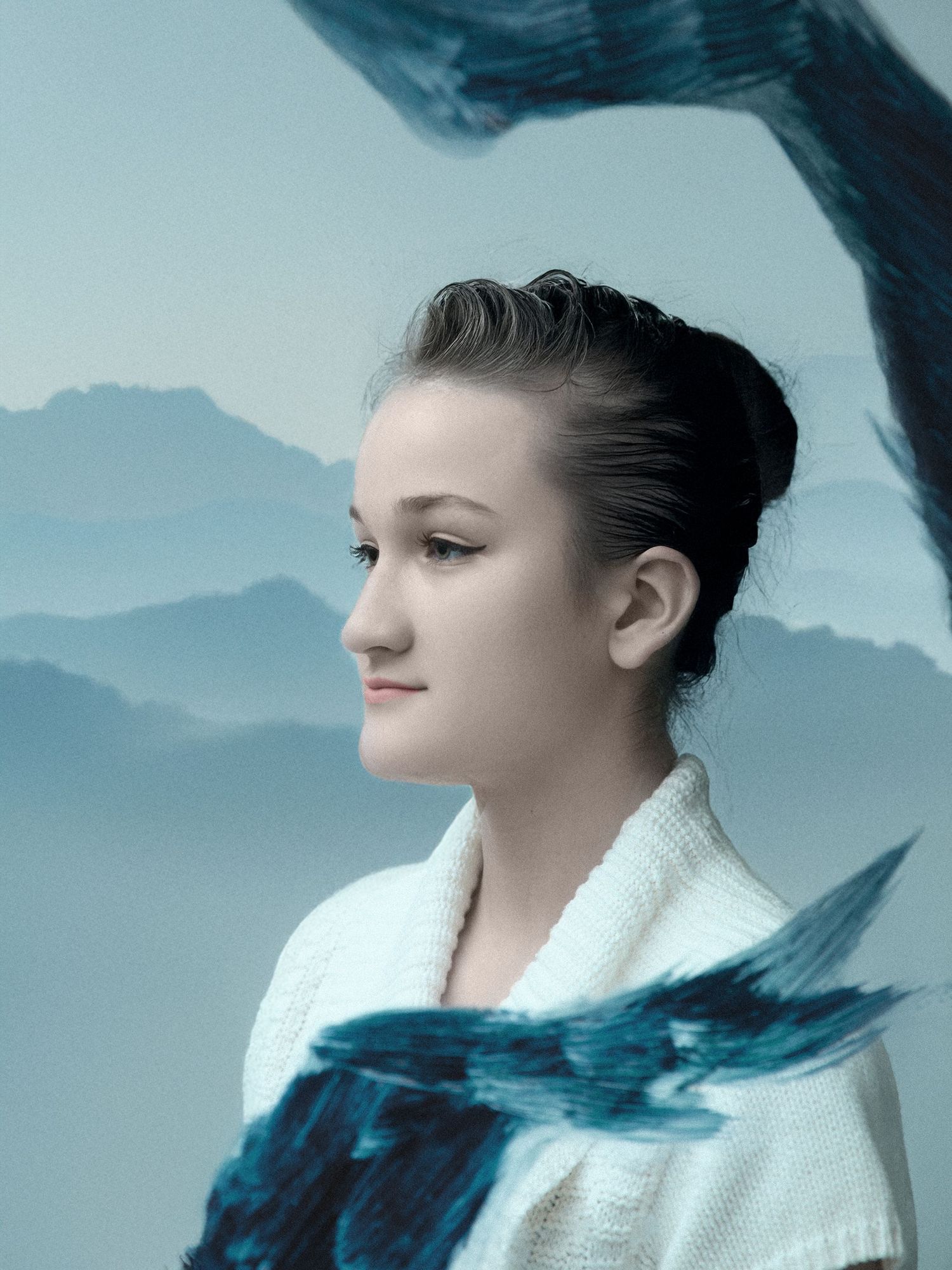 Winter portrait with mountain backdrop features white collar against blue tones.