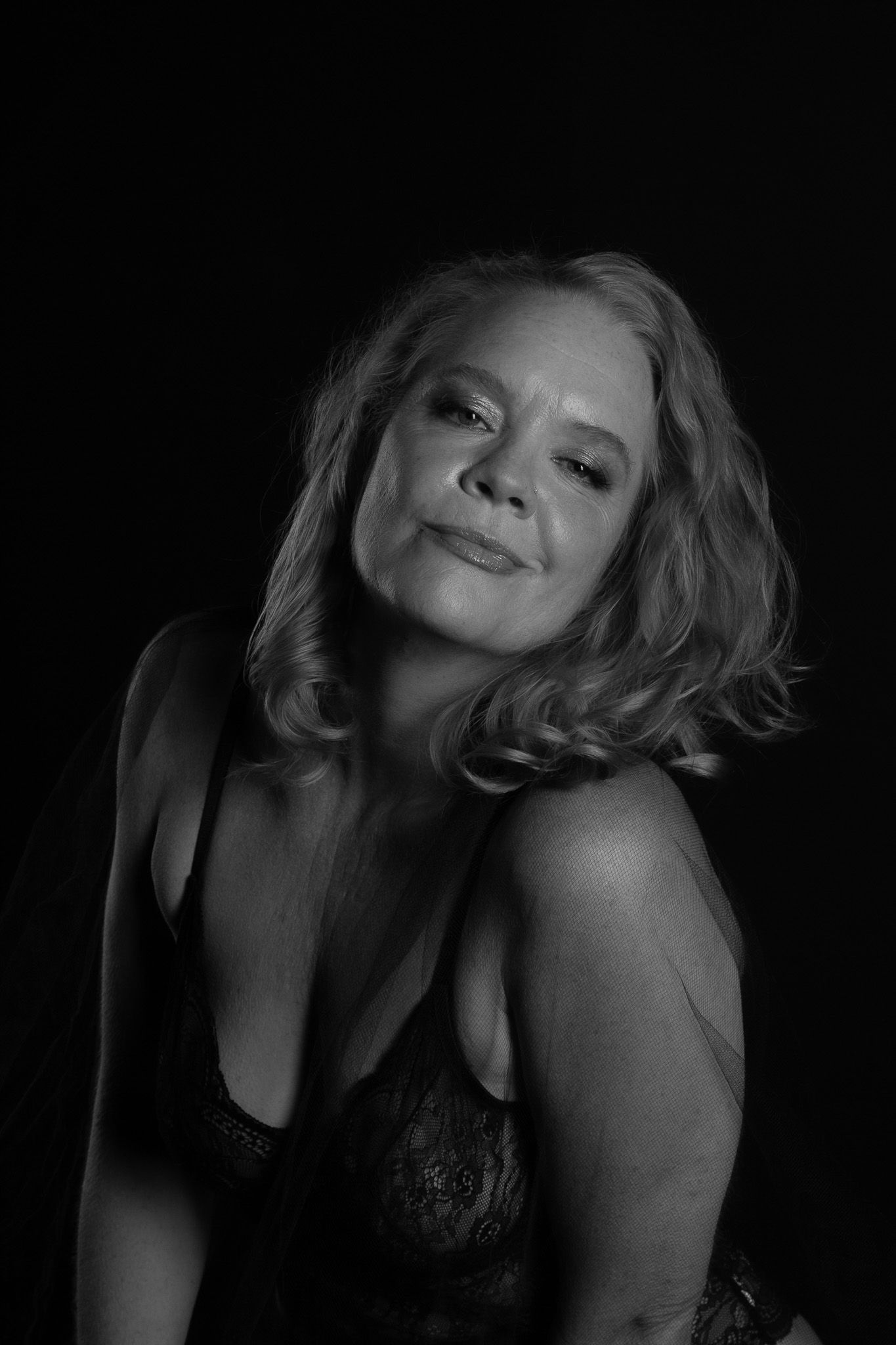 A series of dramatic black and white boudoir portraits showing a person posing against a dark background.