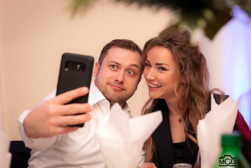 Couple taking a selfie together at an elegant indoor event.