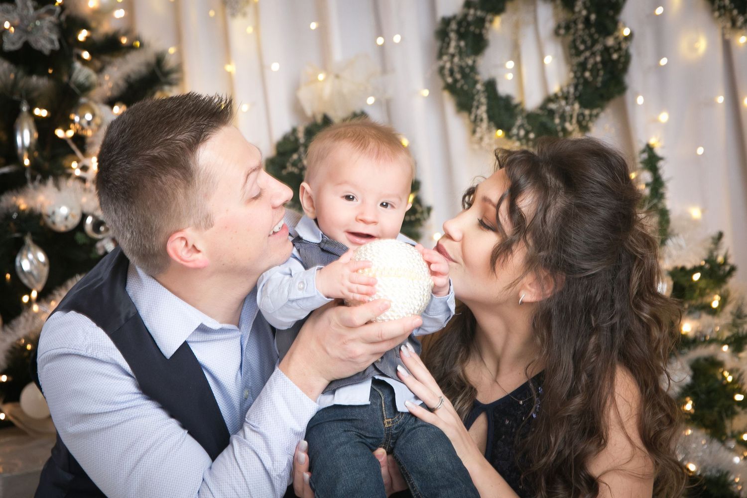 Holiday family portrait session with Christmas decorations and string lights in the background.