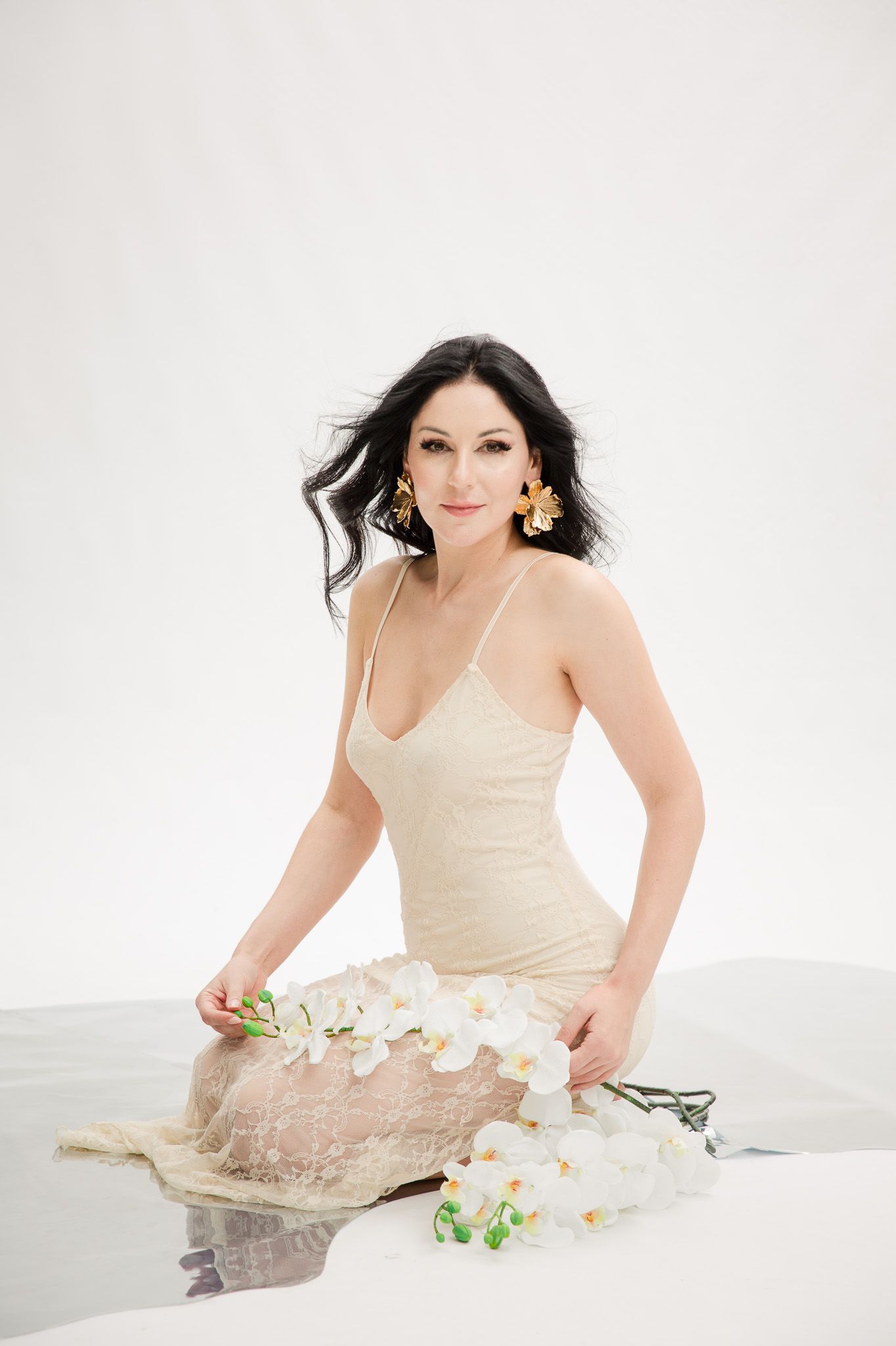 Portrait session featuring white orchids and cream-colored dress against bright white background.