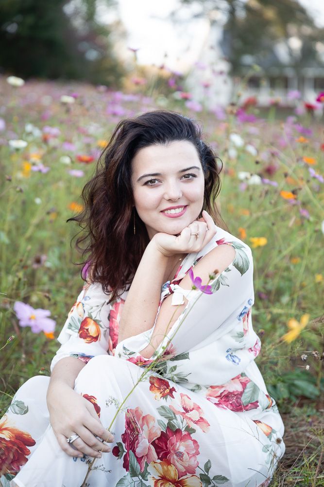 Person lying in wildflower meadow wearing white floral dress in summer.