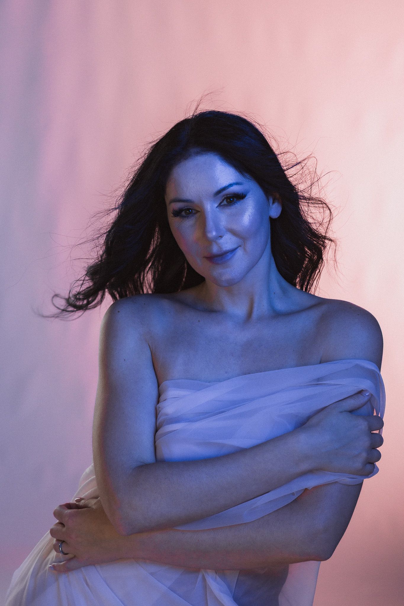 Artistic portrait with dramatic pink and blue lighting creating moody atmosphere.