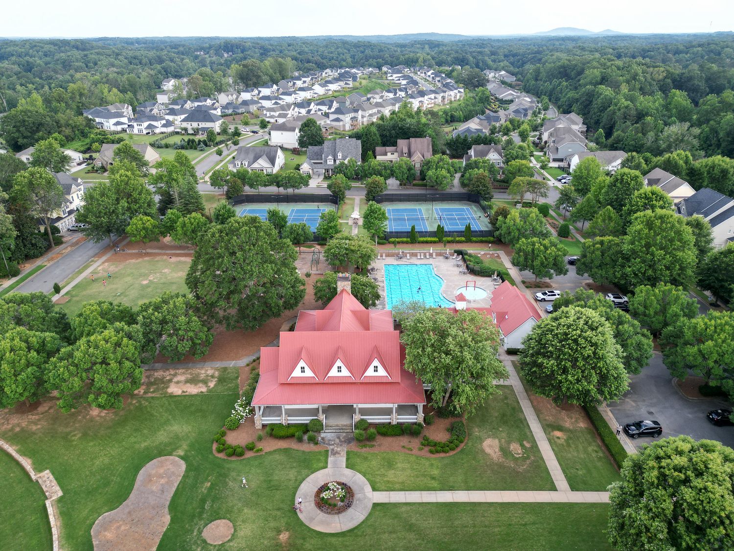 Aerial view of a residential community with tennis courts and swimming pool amenities.
