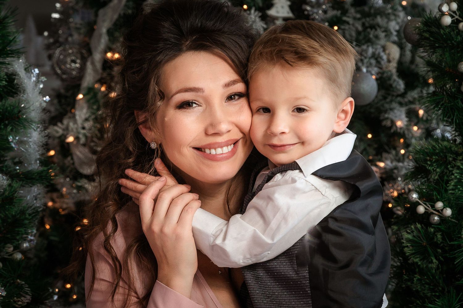 Holiday portrait session against decorated Christmas tree background with soft lighting.