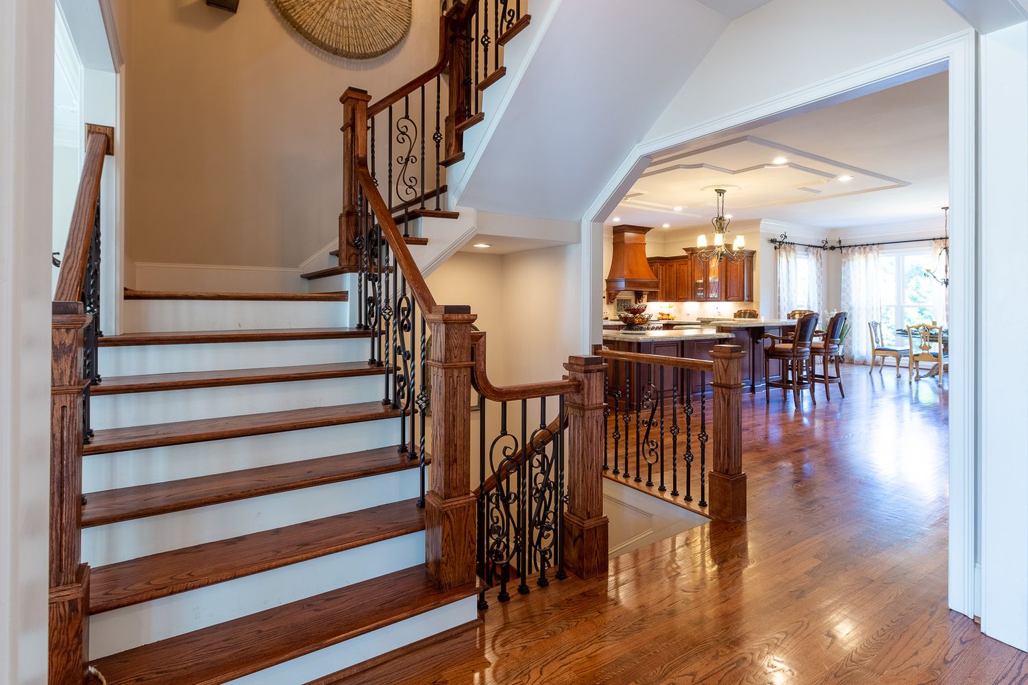Wooden staircase with ornate railings and polished hardwood floors in an open foyer.