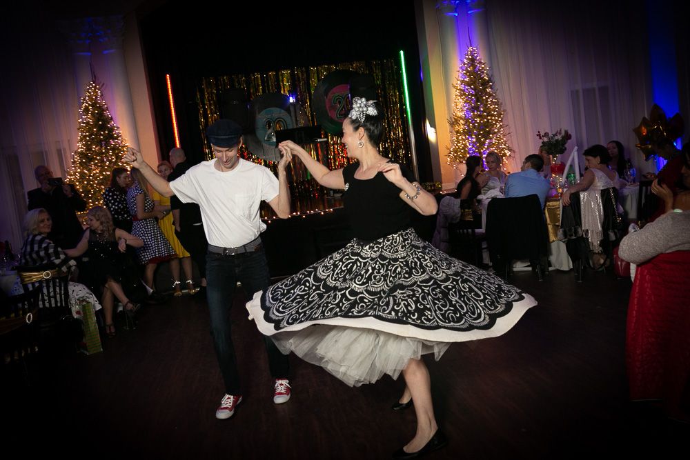 Dancers performing at a festive celebration with dramatic lighting and decorations.