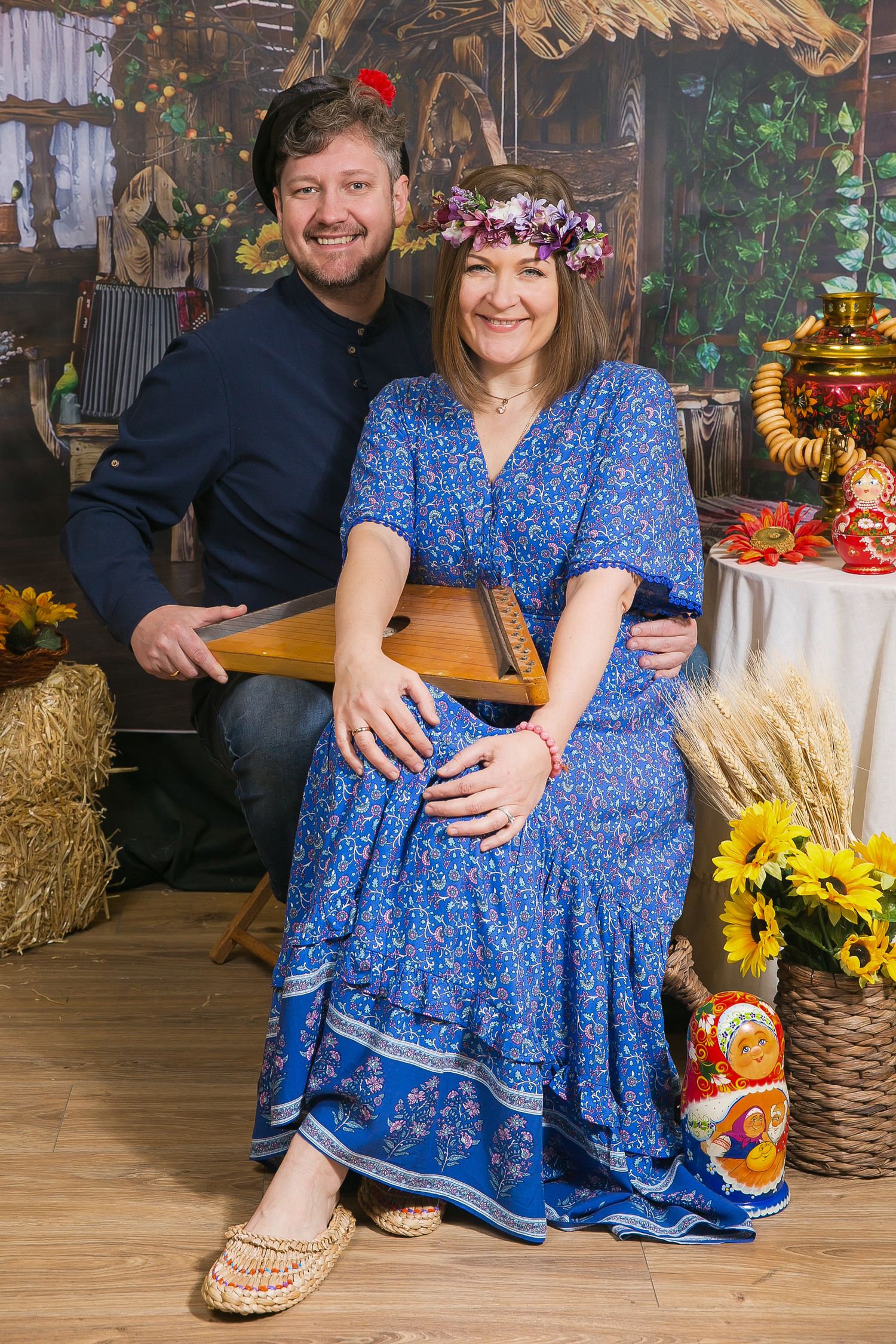 Rustic photo session setup with blue floral dress, hay bales, and sunflower decorations.