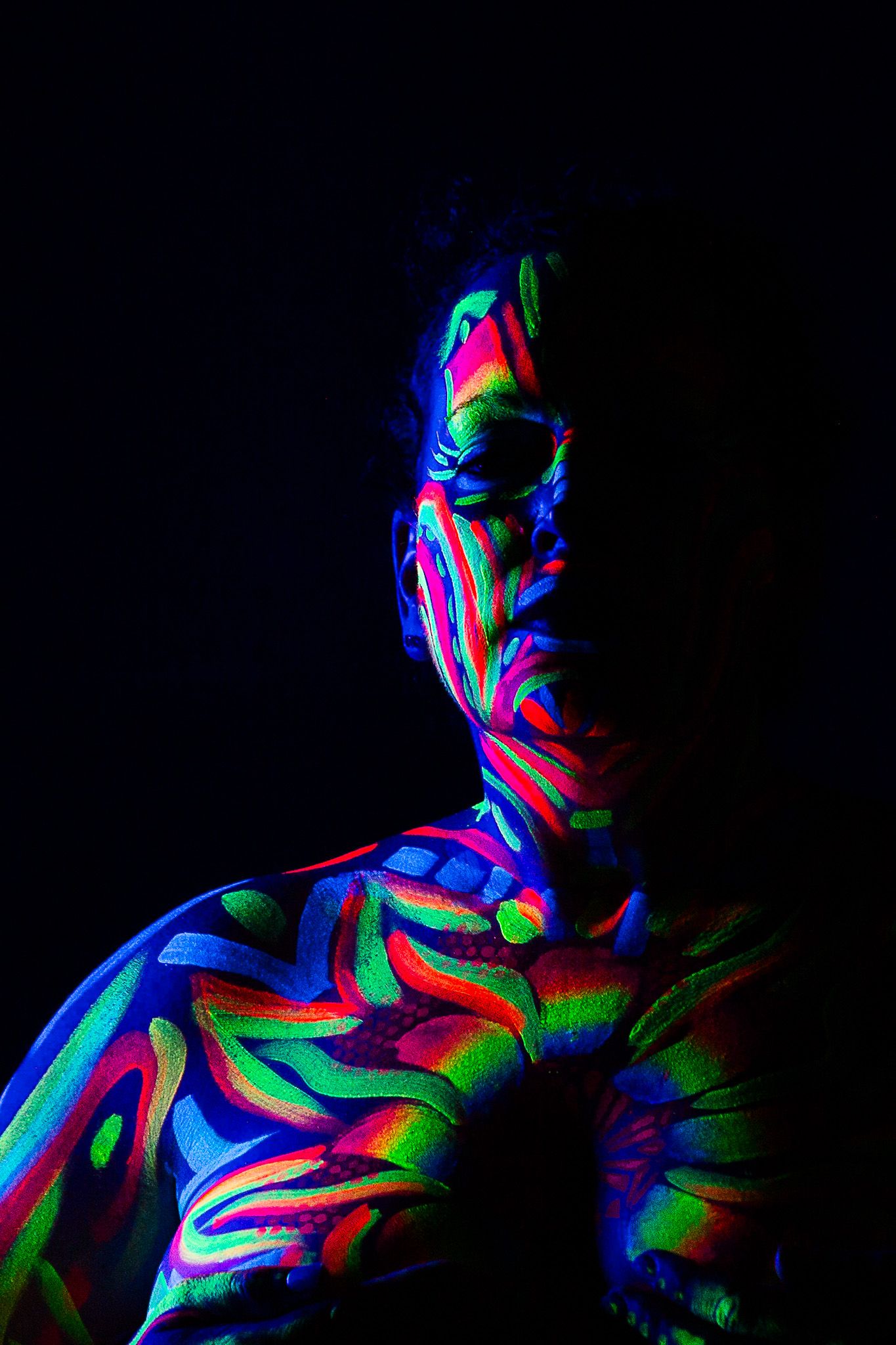 Abstract body art featuring neon swirls and patterns under UV light.