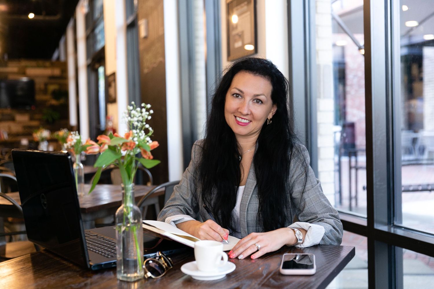 Interior cafe scene with coffee cup and flowers on table by window.