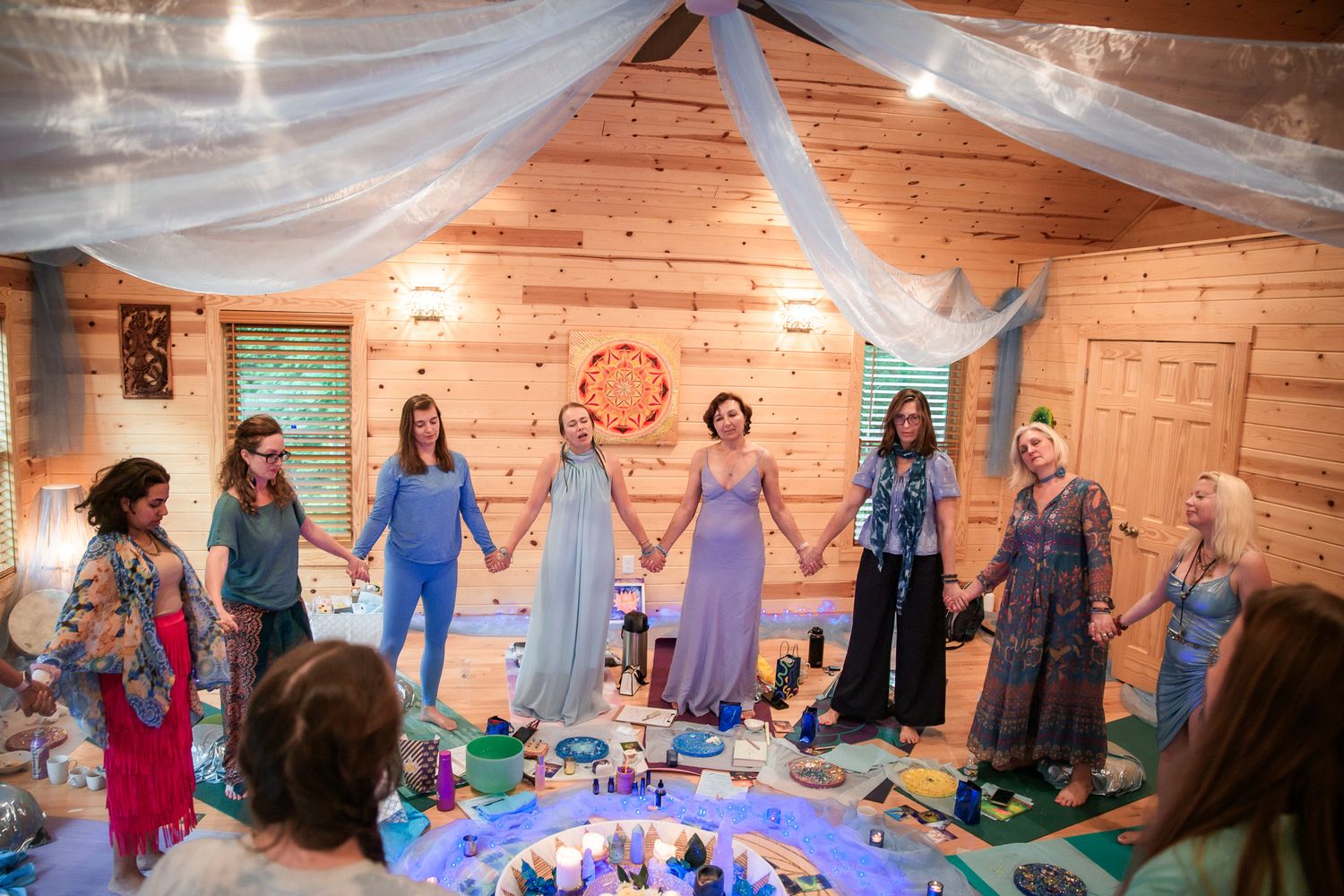 People joining hands in a circle during a spiritual or ceremonial gathering.