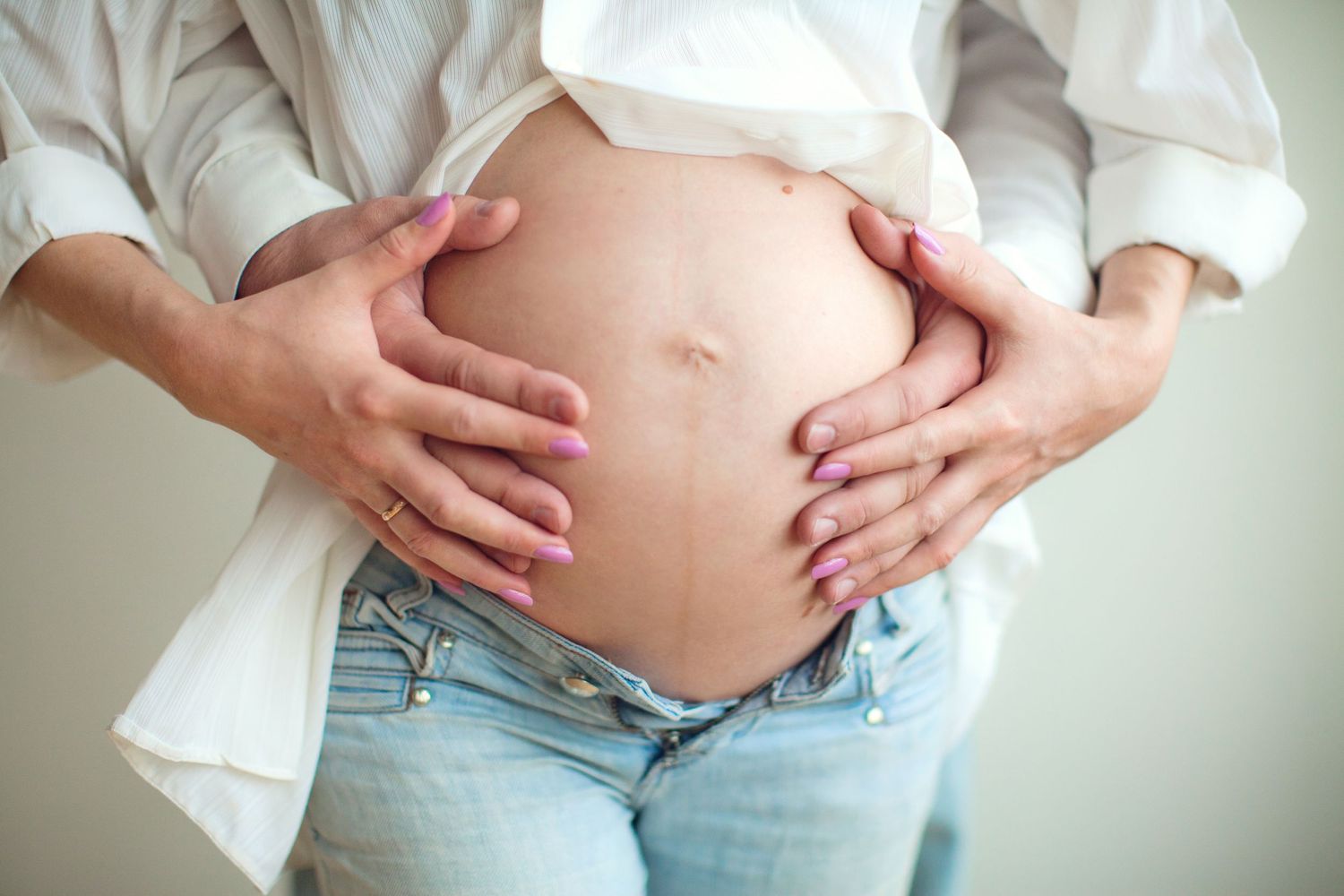 Intimate belly progression photos showing growing baby bump in casual home setting.