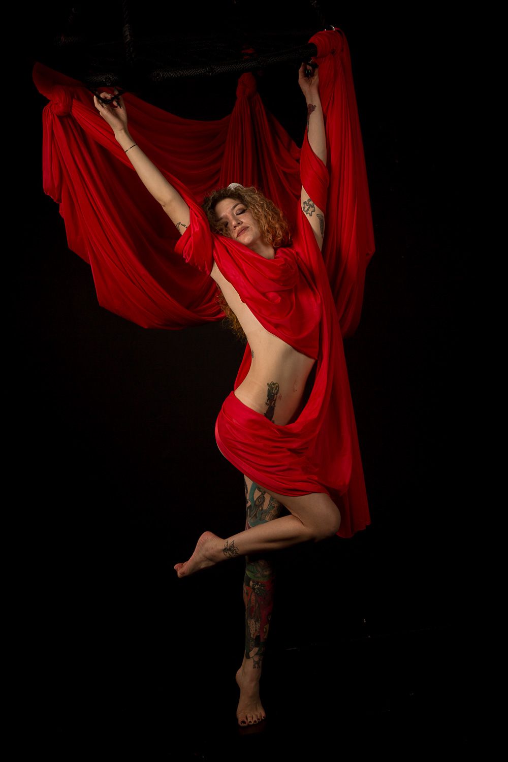 Dynamic dance poses with flowing red fabric against black background.