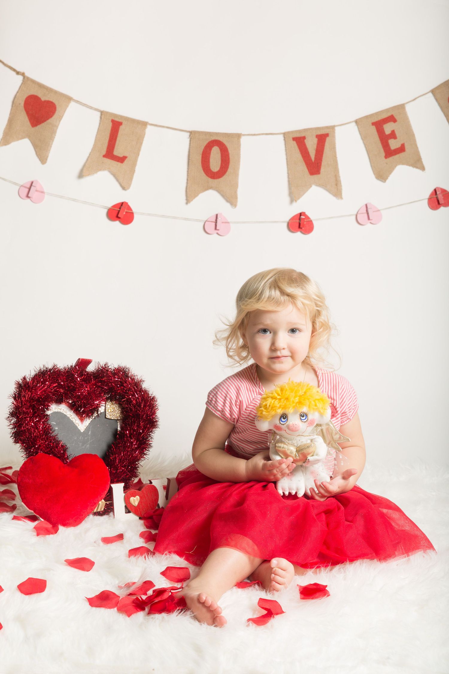 Valentine's day themed photo setup with red hearts, LOVE banner, and festive decorations.