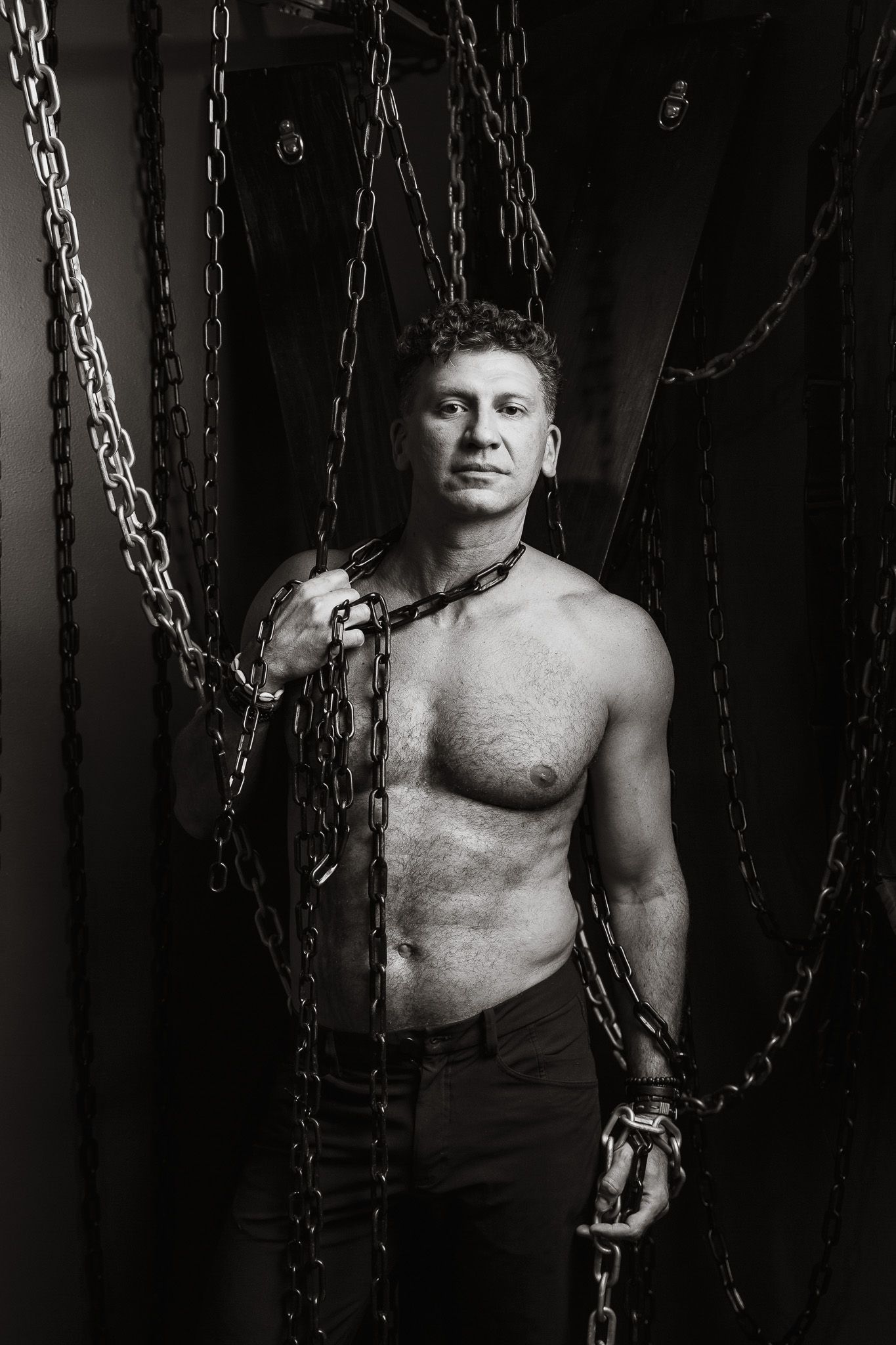 Dramatic black and white portrait with metal chains creating an edgy industrial aesthetic.