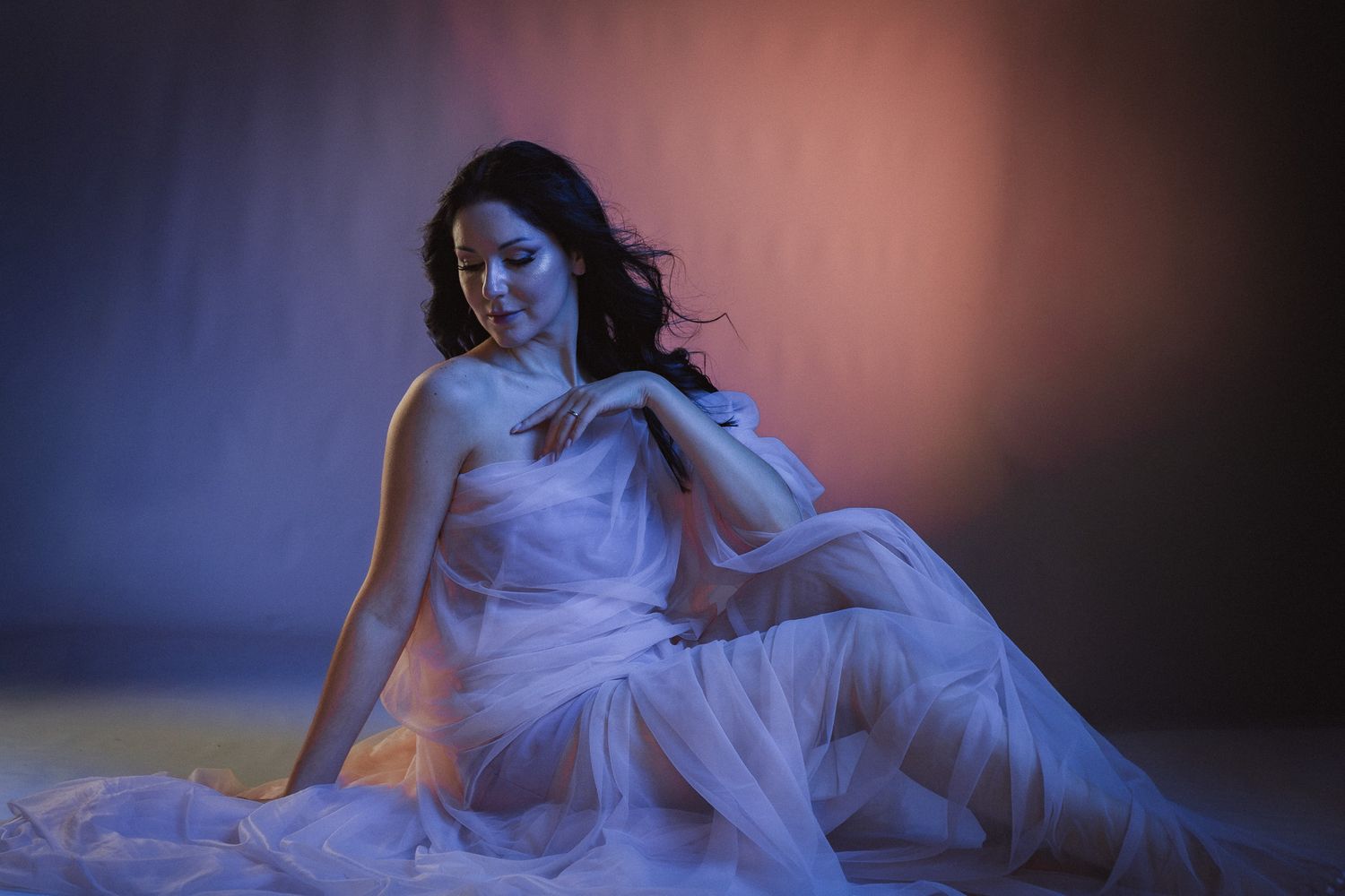Dreamy portrait in flowing white fabric with dramatic lighting and shadows.